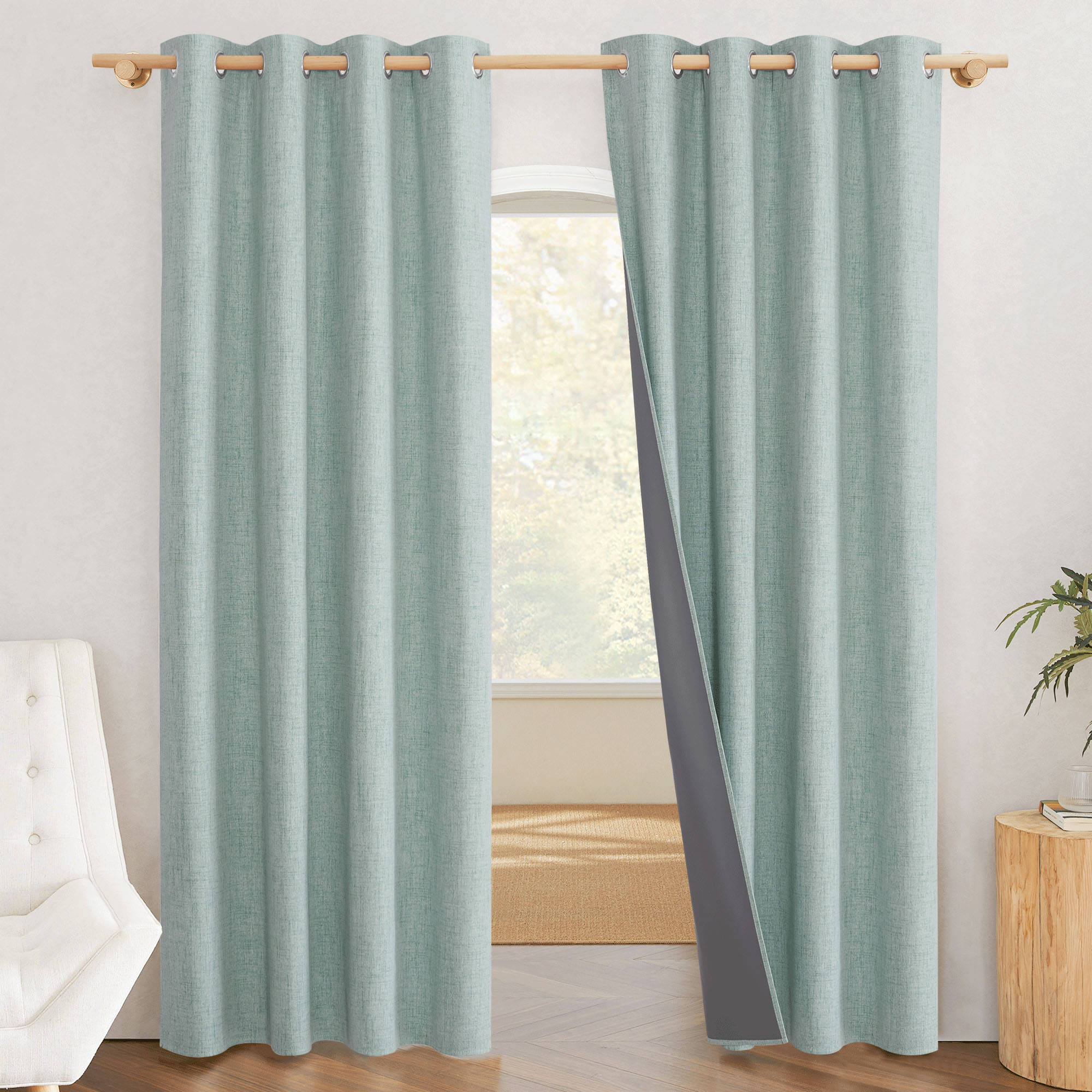 Sage green linen blackout curtain with a grommet top, pulled aside to show its dark grey 100% blackout liner.