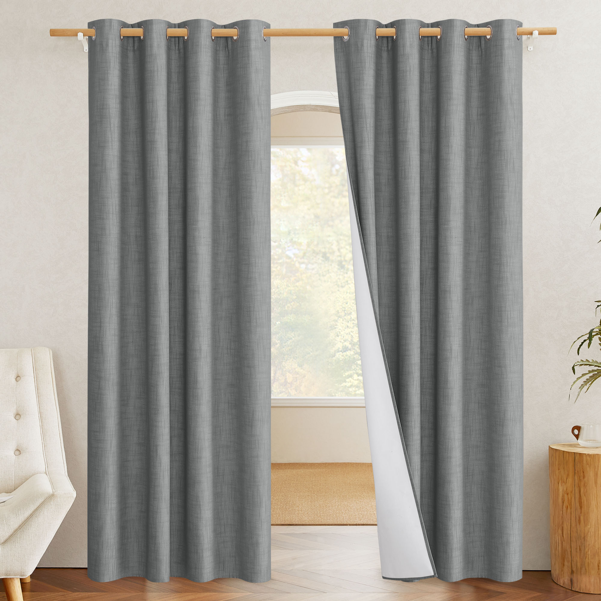 Grey linen-textured blackout curtains with silver grommets. One panel is pulled back to display the white thermal blackout liner.