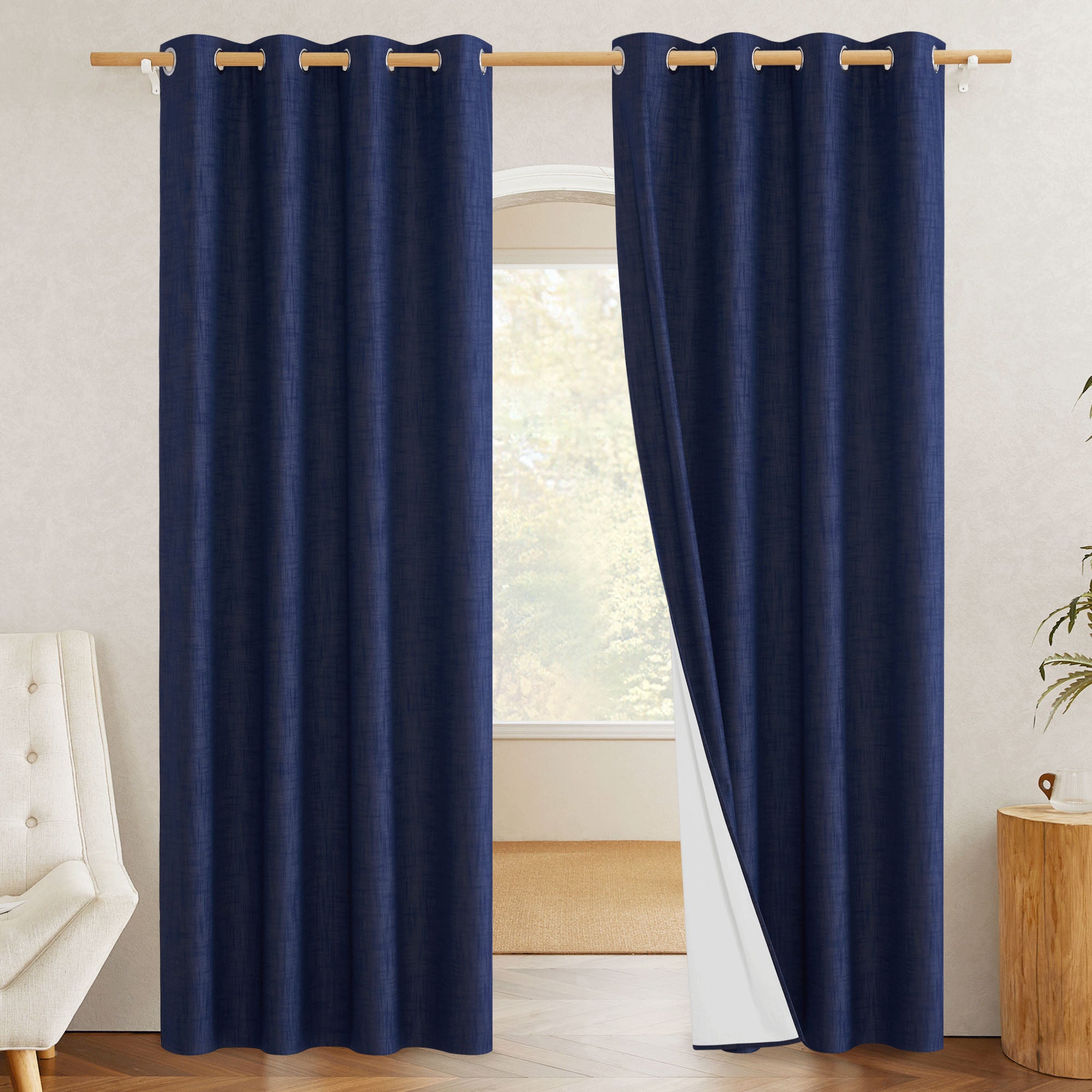 Navy blue blackout linen curtains with one panel pulled back to show the white thermal blackout lining on the reverse side.