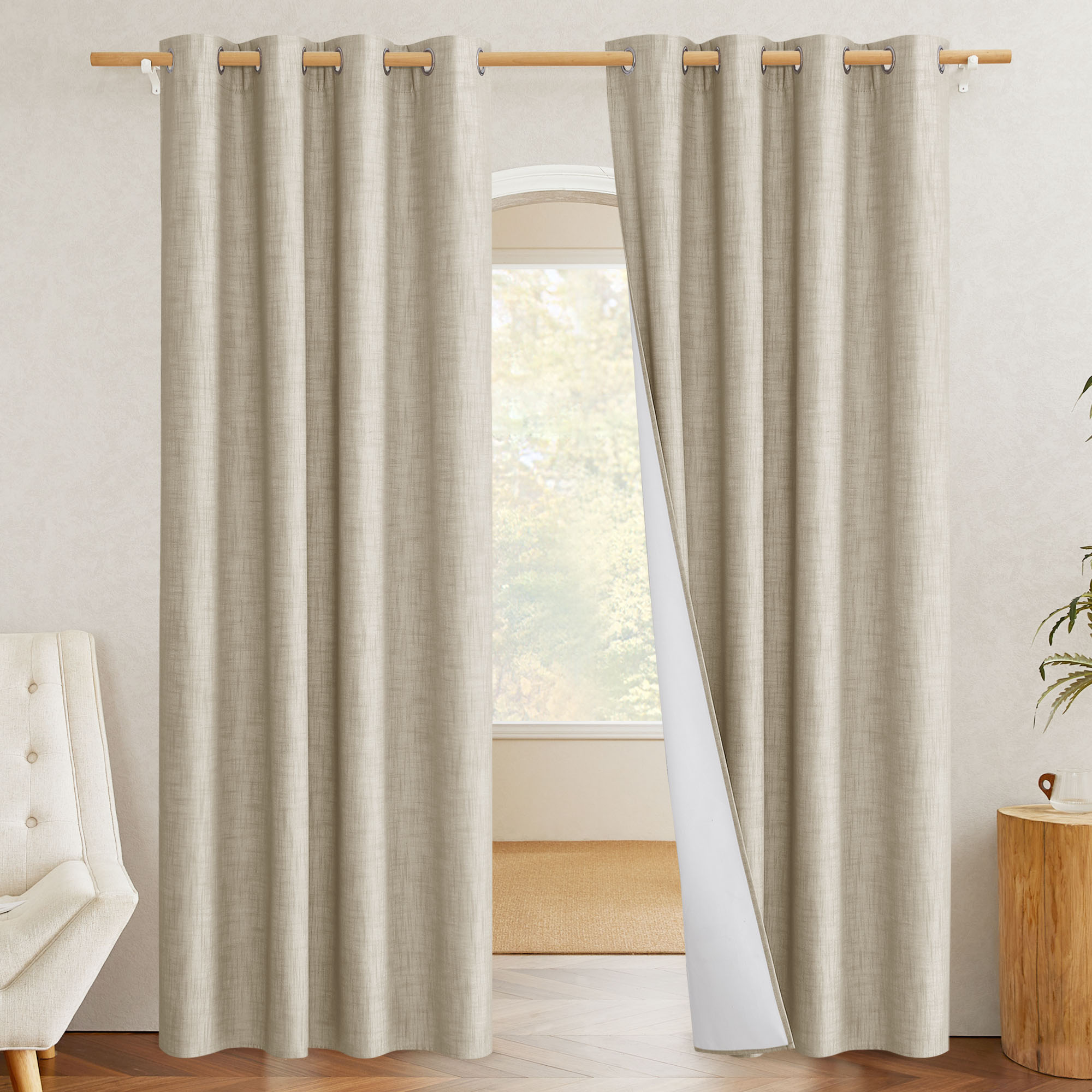 A pair of beige linen blackout curtains, with one panel pulled back to show the white thermal lining inside.
