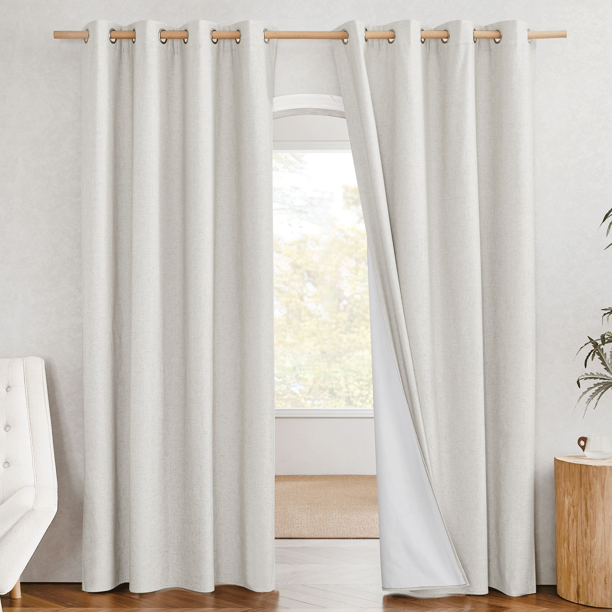 Off-white grommet blackout linen curtains hung in a room, with one panel pulled back revealing the white blackout lining.