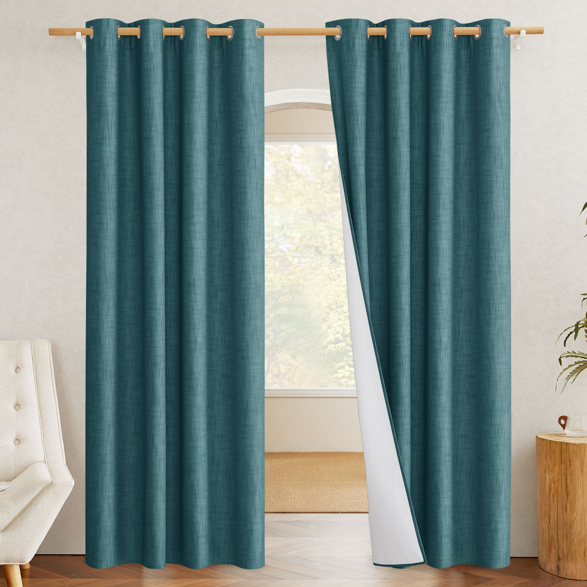 A pair of teal linen blackout curtains with one panel pulled back to reveal the white thermal liner.