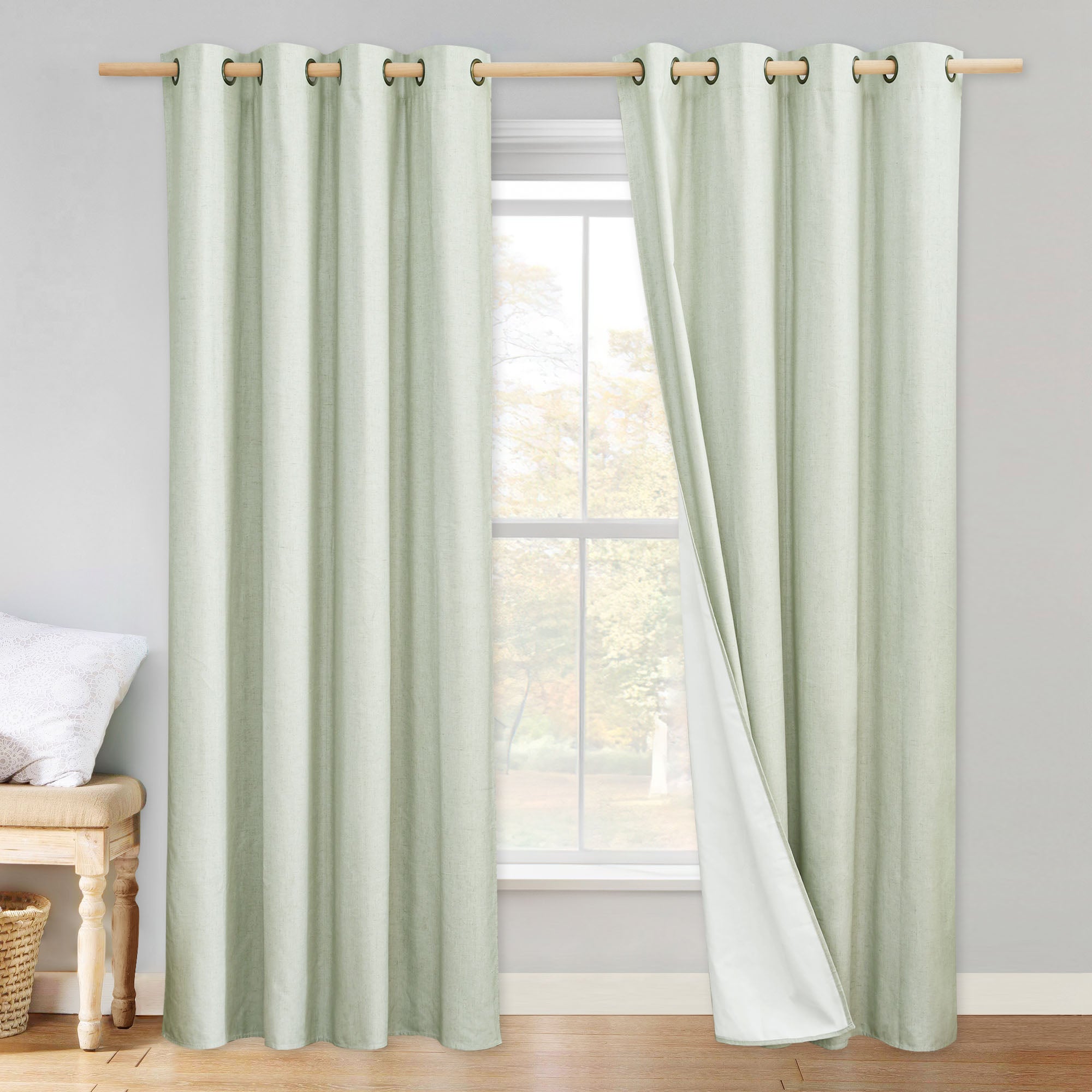 Sage green linen blackout curtains on a rod. The right panel is pulled back to show the white blackout lining.