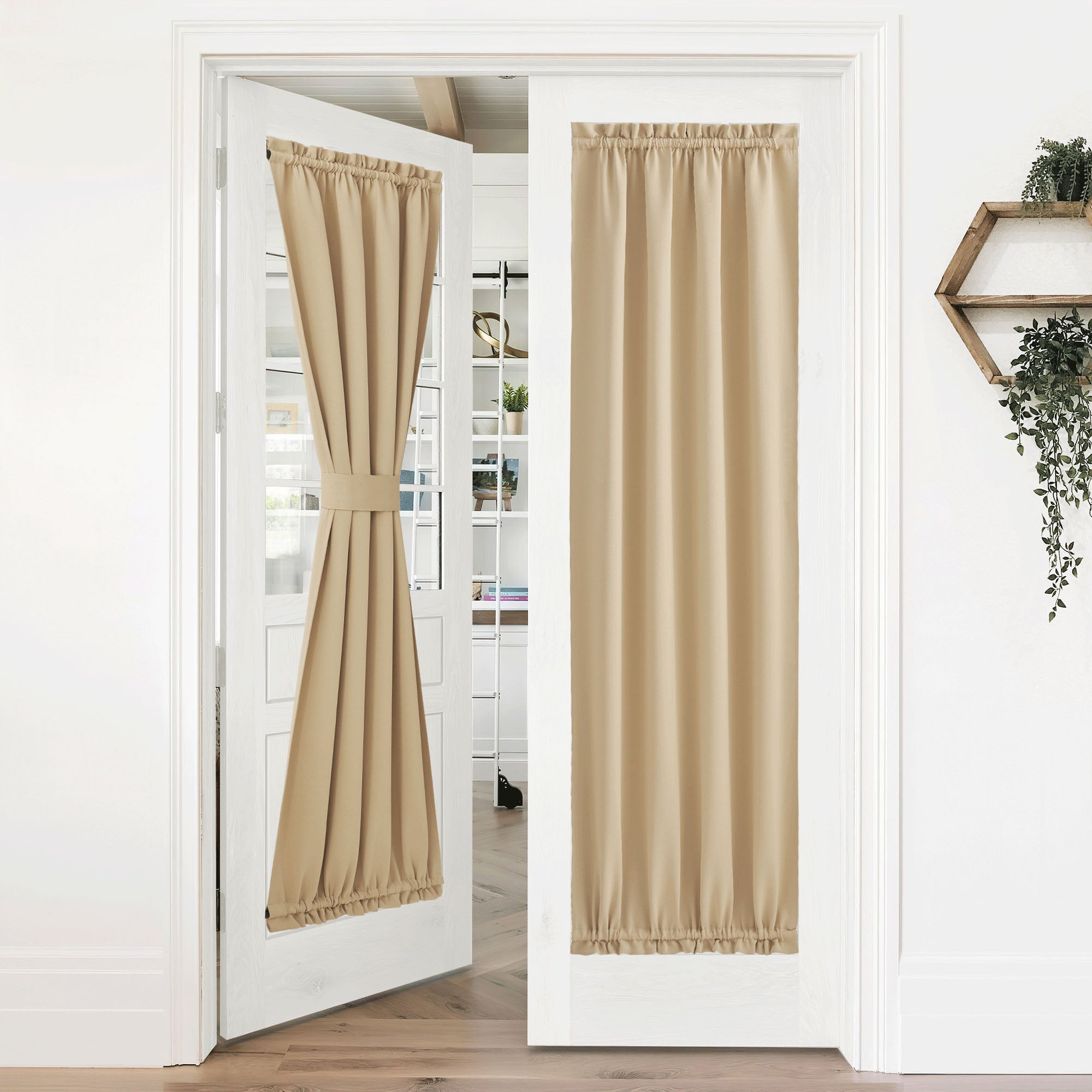 Two light beige blackout door panel curtains on French doors, one tied back, enhancing privacy and light control.