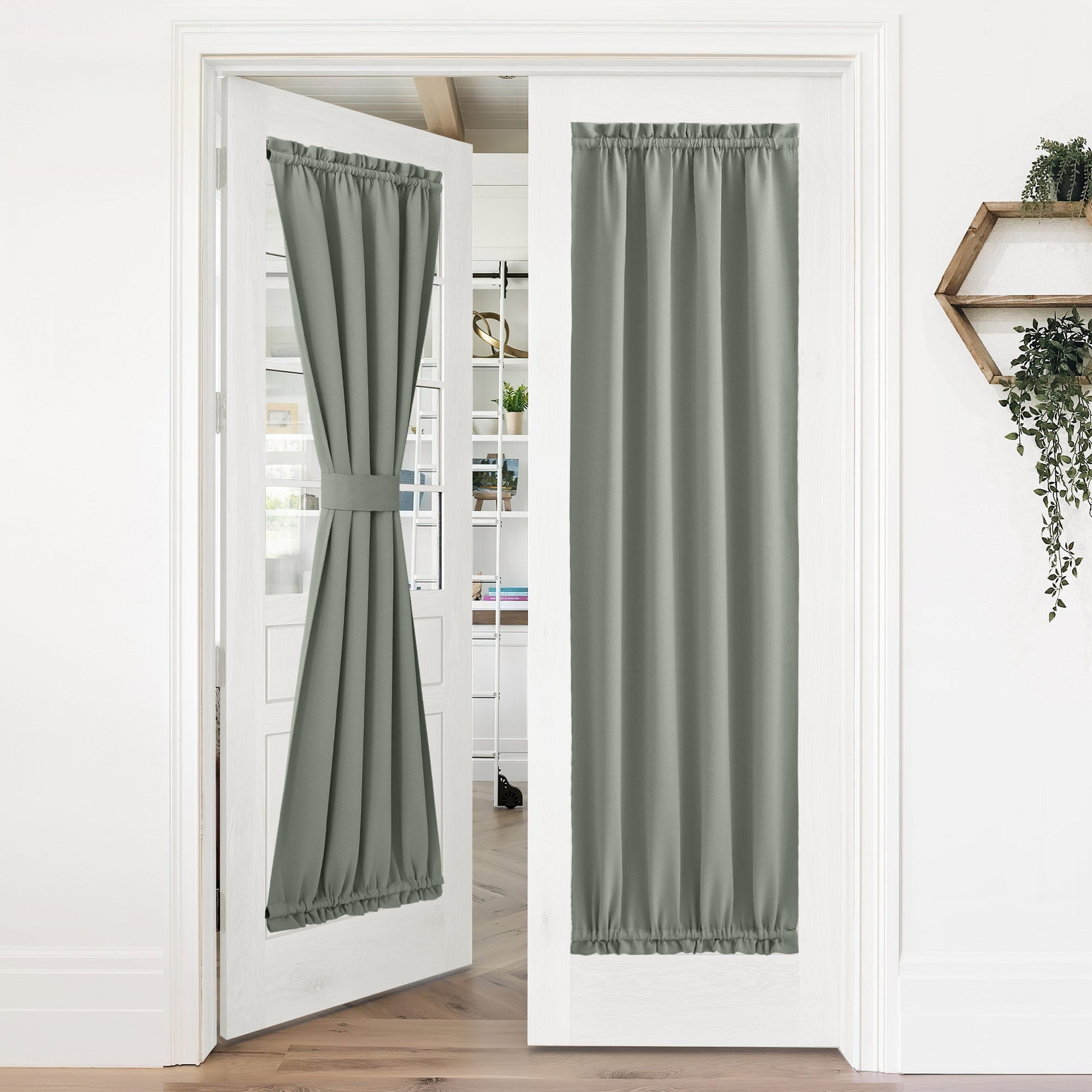 Sage green 50% blackout rod pocket door curtains on white French doors, one tied back, one fully covering glass for privacy.