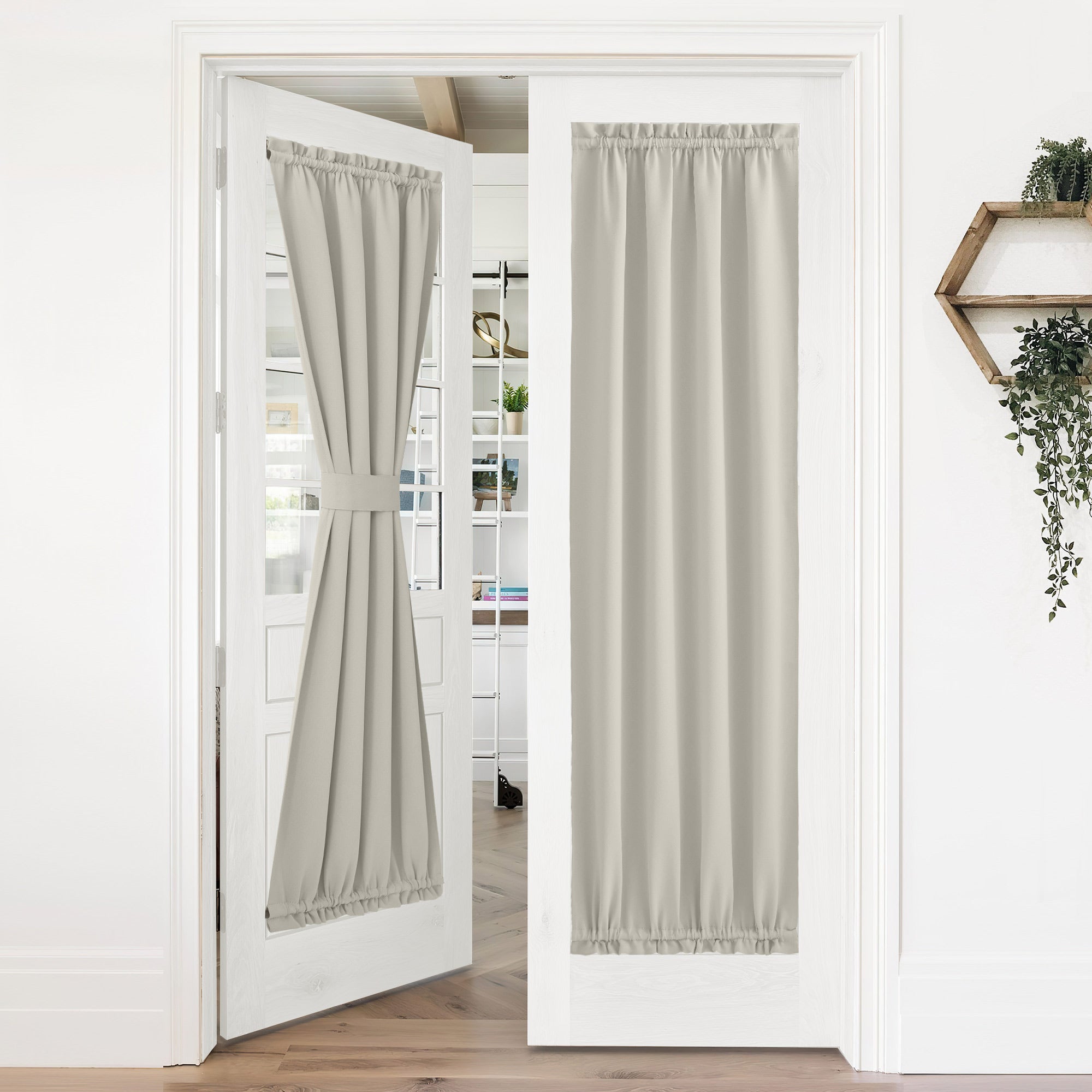 Pair of beige 50% blackout privacy door curtains on white french doors. One tied back; the other fully covers the window.