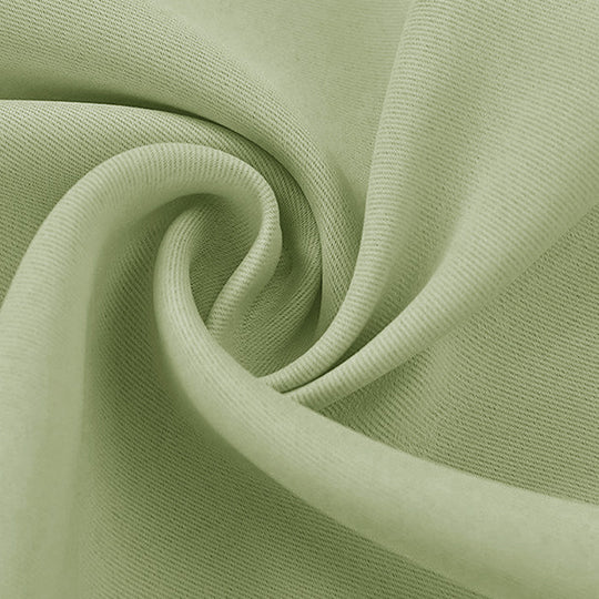 Close-up of a light green blackout fabric swatch, folded to reveal its soft texture and subtle diagonal weave.