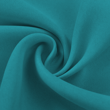 Close-up of a teal blackout fabric swatch, folded to reveal its smooth texture and rich color