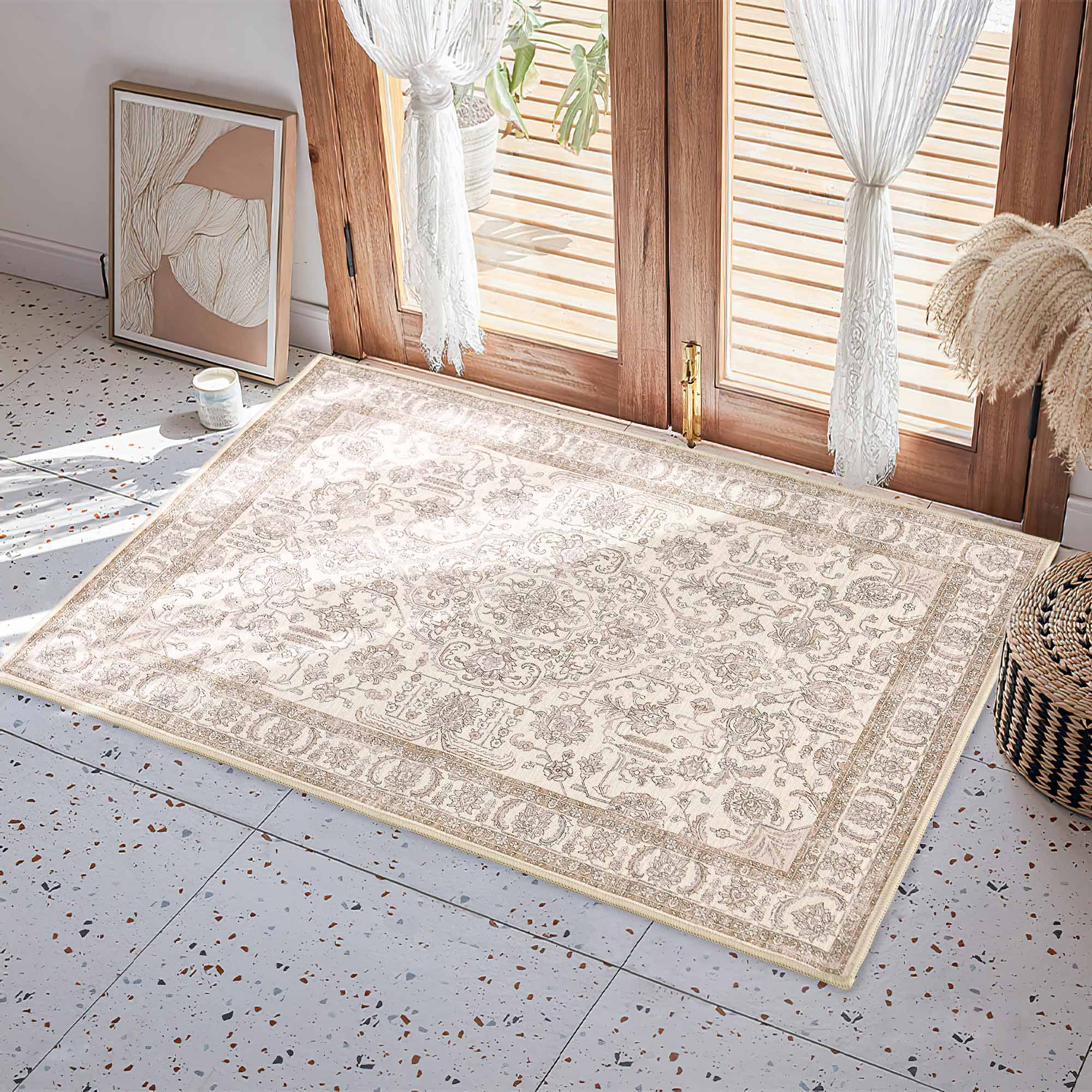 Cream chenille area rug with intricate beige floral pattern and border on a tiled floor by a wooden door, ideal for an entryway.