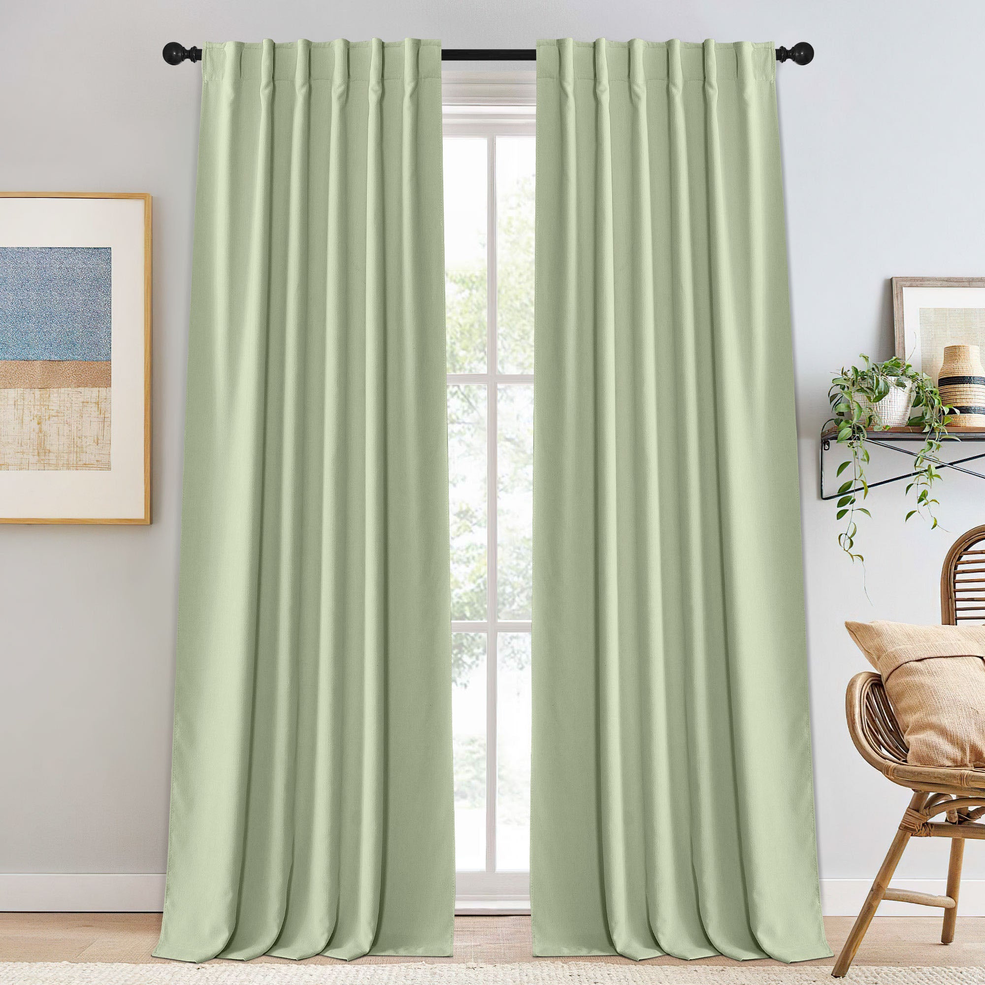 Full-length light green chenille blackout curtains with neat pinch pleats on a black rod, covering a window in a bright room.