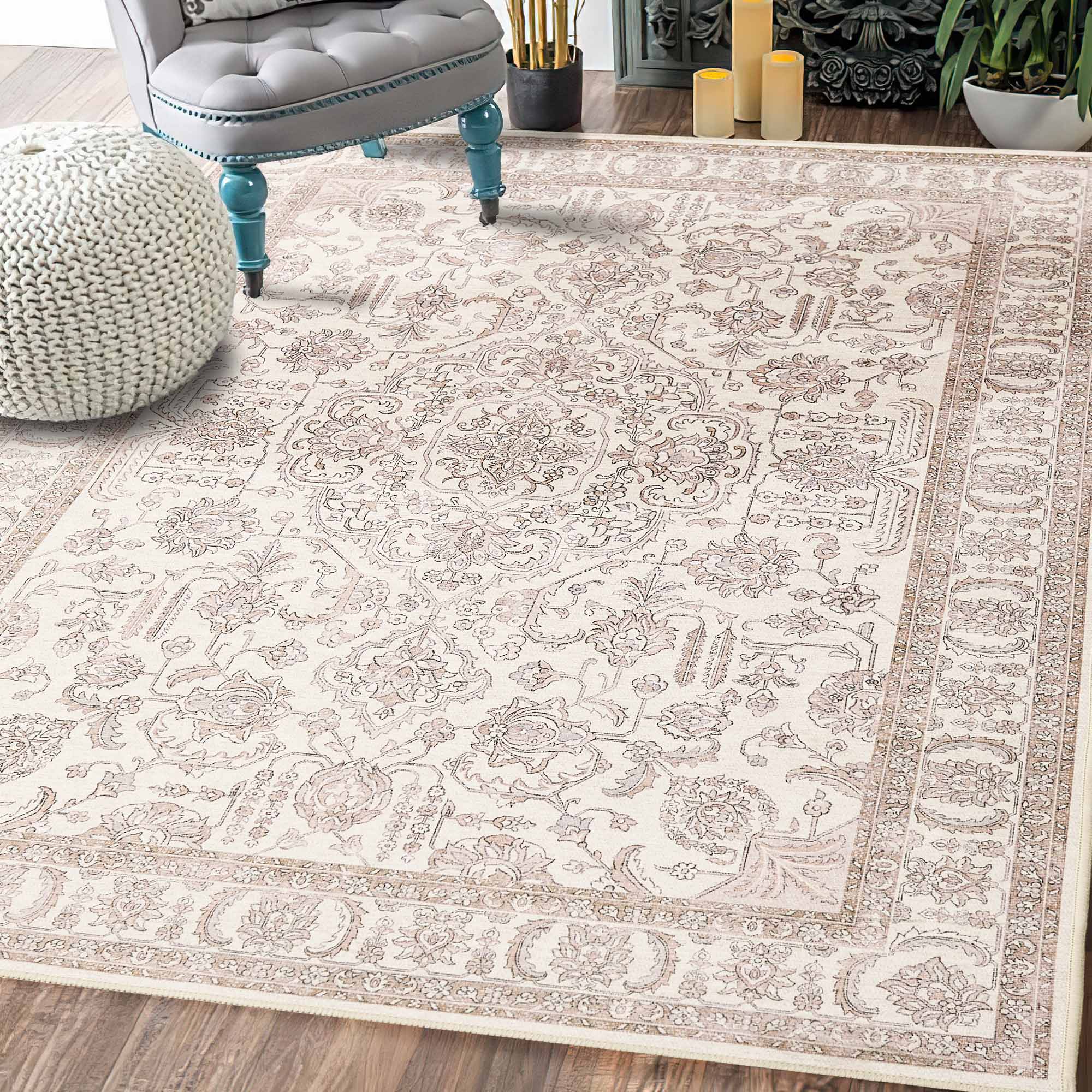 Cream chenille area rug with intricate floral and medallion pattern detail. A gray armchair and knitted pouf sit on the rug.