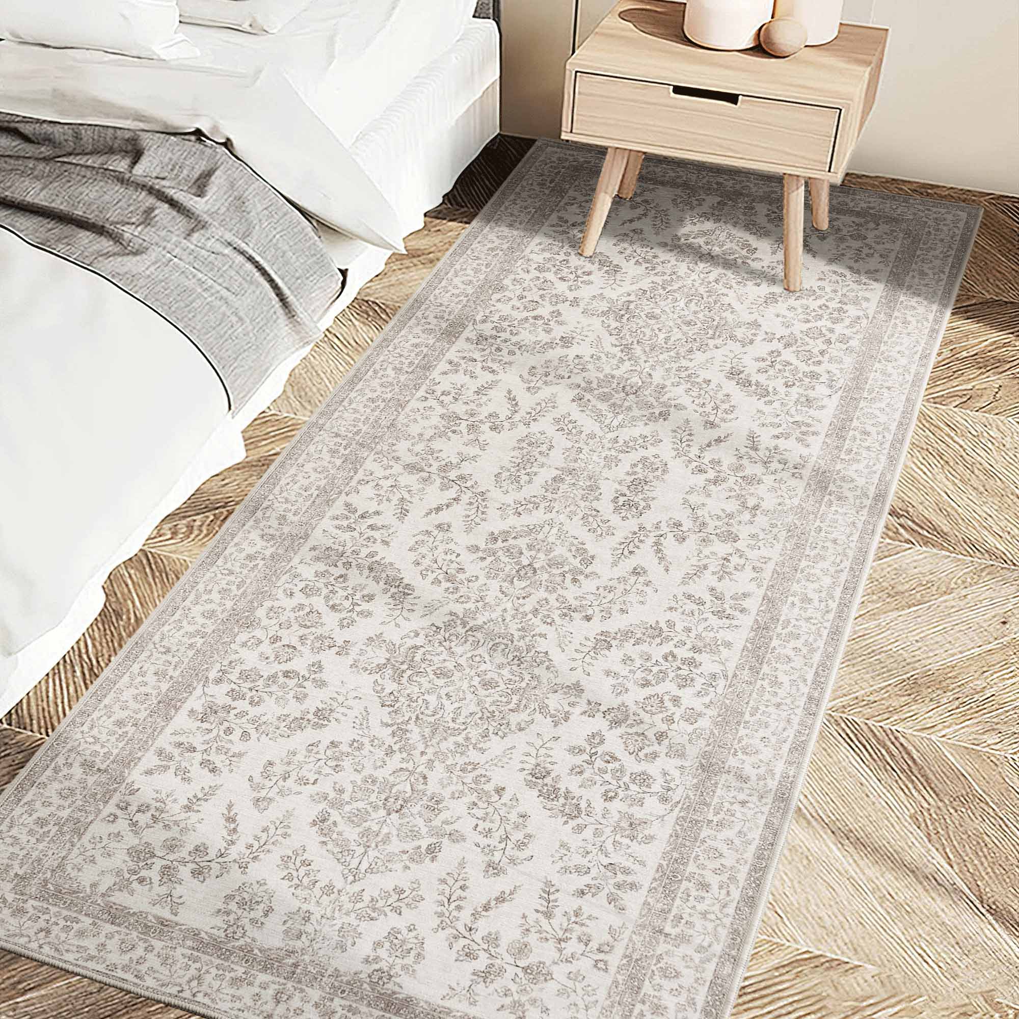 Long light chenille runner rug with subtle floral pattern next to a bed and wooden nightstand in a bedroom.