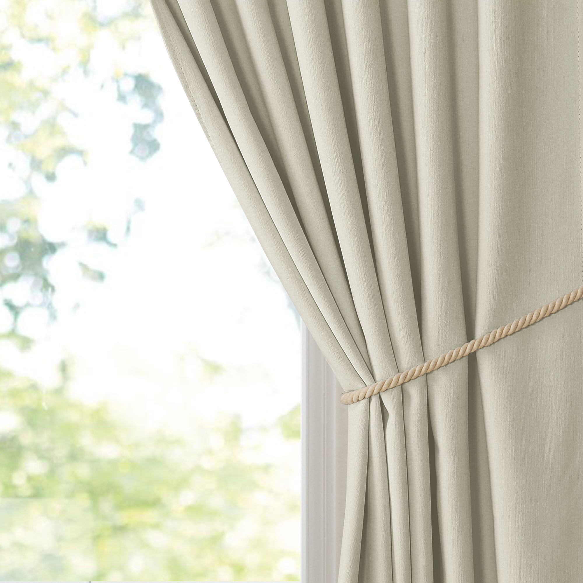 Light beige chenille blackout curtain with a textured finish, elegantly tied back with a natural rope by a window.