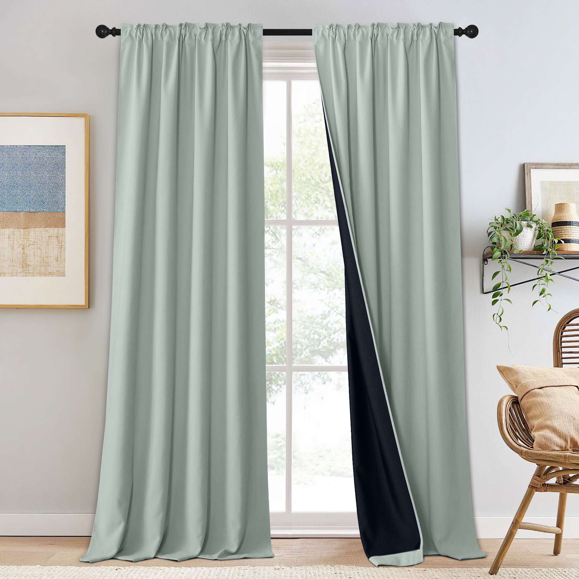 Pale sage green chenille blackout curtains, one panel slightly open to reveal the dark lining, hung on a rod over a window.