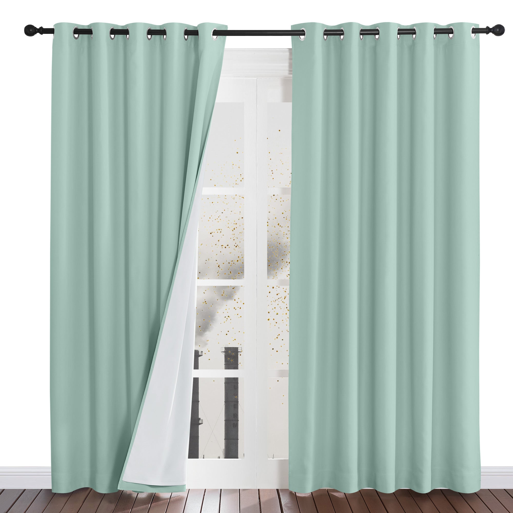 A mint green four-layer dustproof curtain pulled back to reveal its white lining in front of a window with a city view.