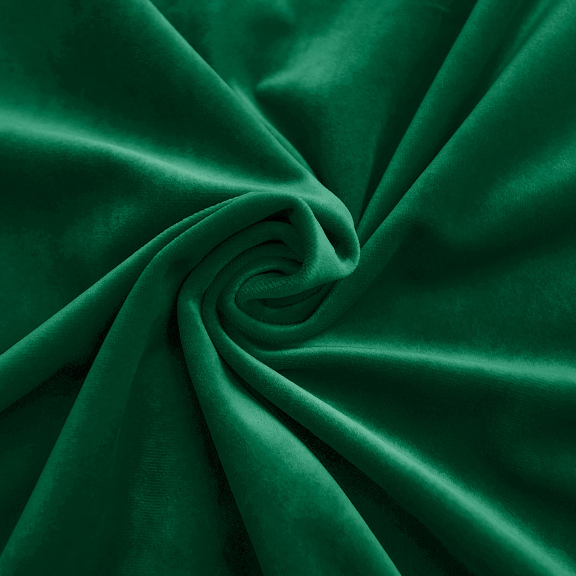 Close-up of rich emerald green velvet fabric swirled to highlight its luxurious texture and beautiful sheen.