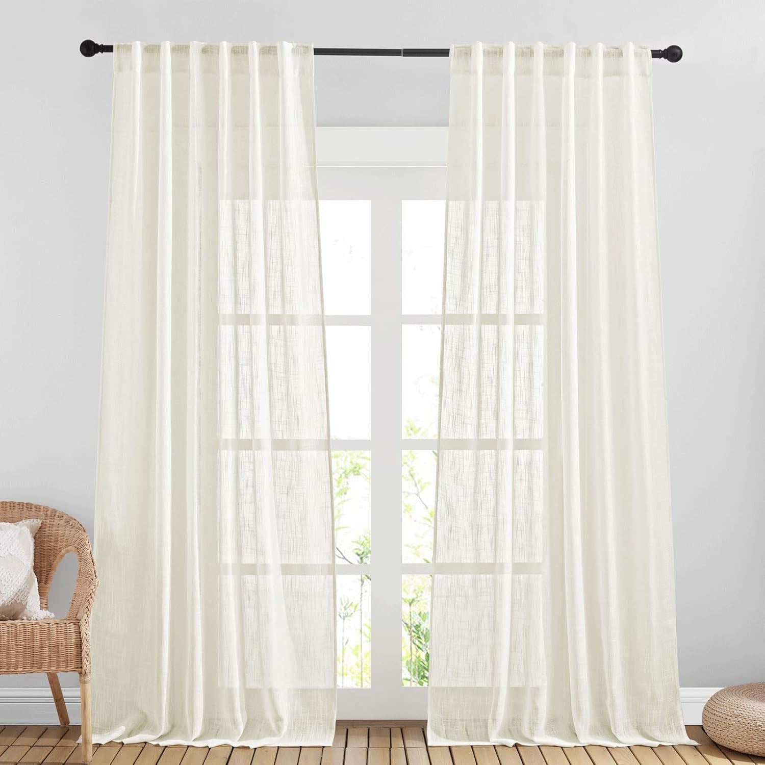 A pair of off-white faux linen semitransparent curtains gently filtering sunlight through a large window in a modern living room.