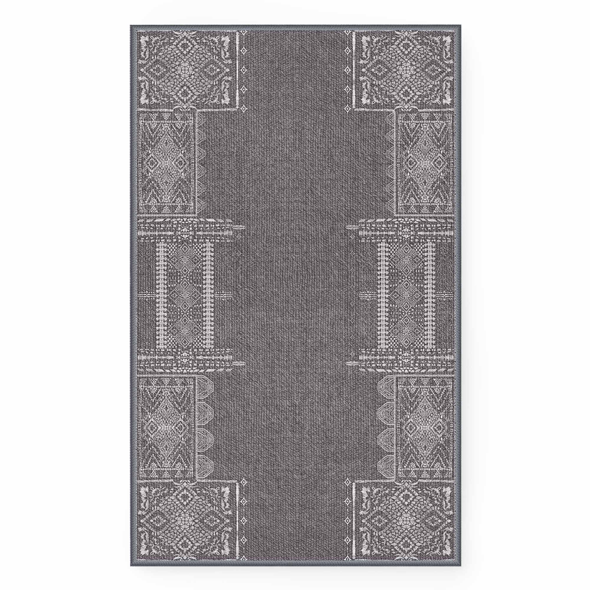 Full view of long dark grey faux wool runner rug with light grey intricate tribal and geometric patterns along the borders.