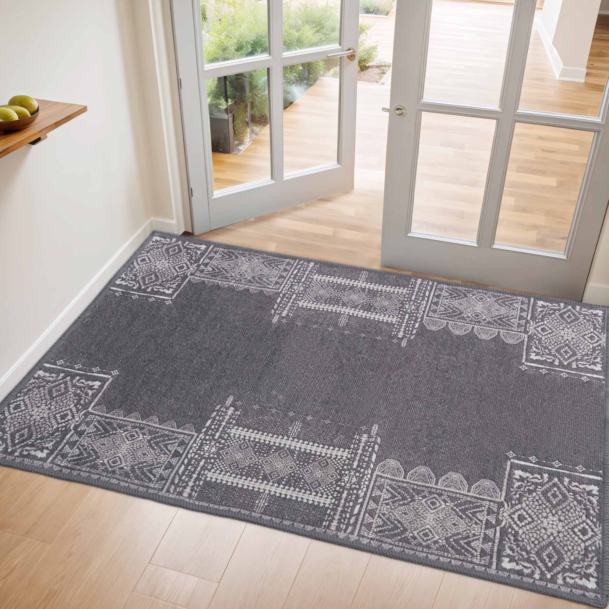 Grey faux wool rug with intricate white geometric patterns on a light wood floor, near open French doors in an entryway.