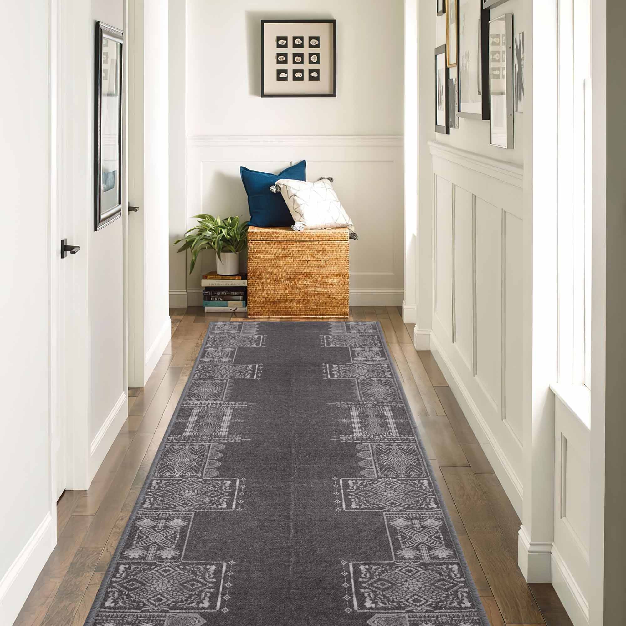 Dark gray faux wool runner rug with light geometric patterns in a hallway with white paneled walls and wood floor.