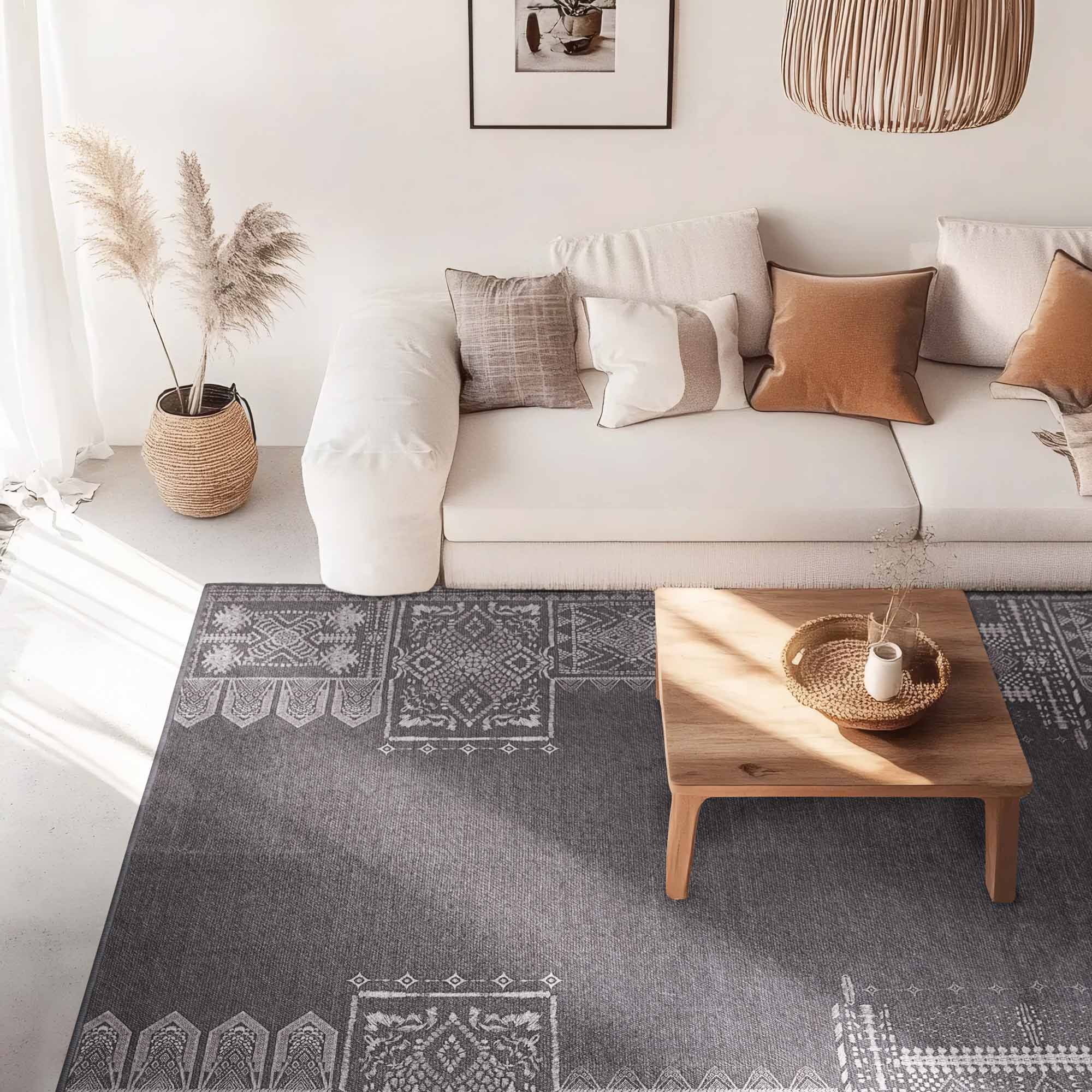 Grey faux wool rug with intricate white patterned sections laid out in a modern living room with a white sofa and wooden coffee table.