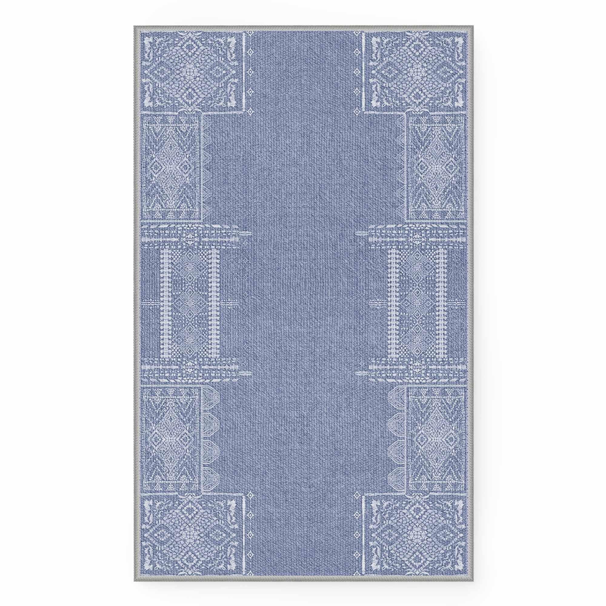 Full overhead view of the blue faux wool rug, featuring white intricate geometric patterns on rectangular sections and borders.