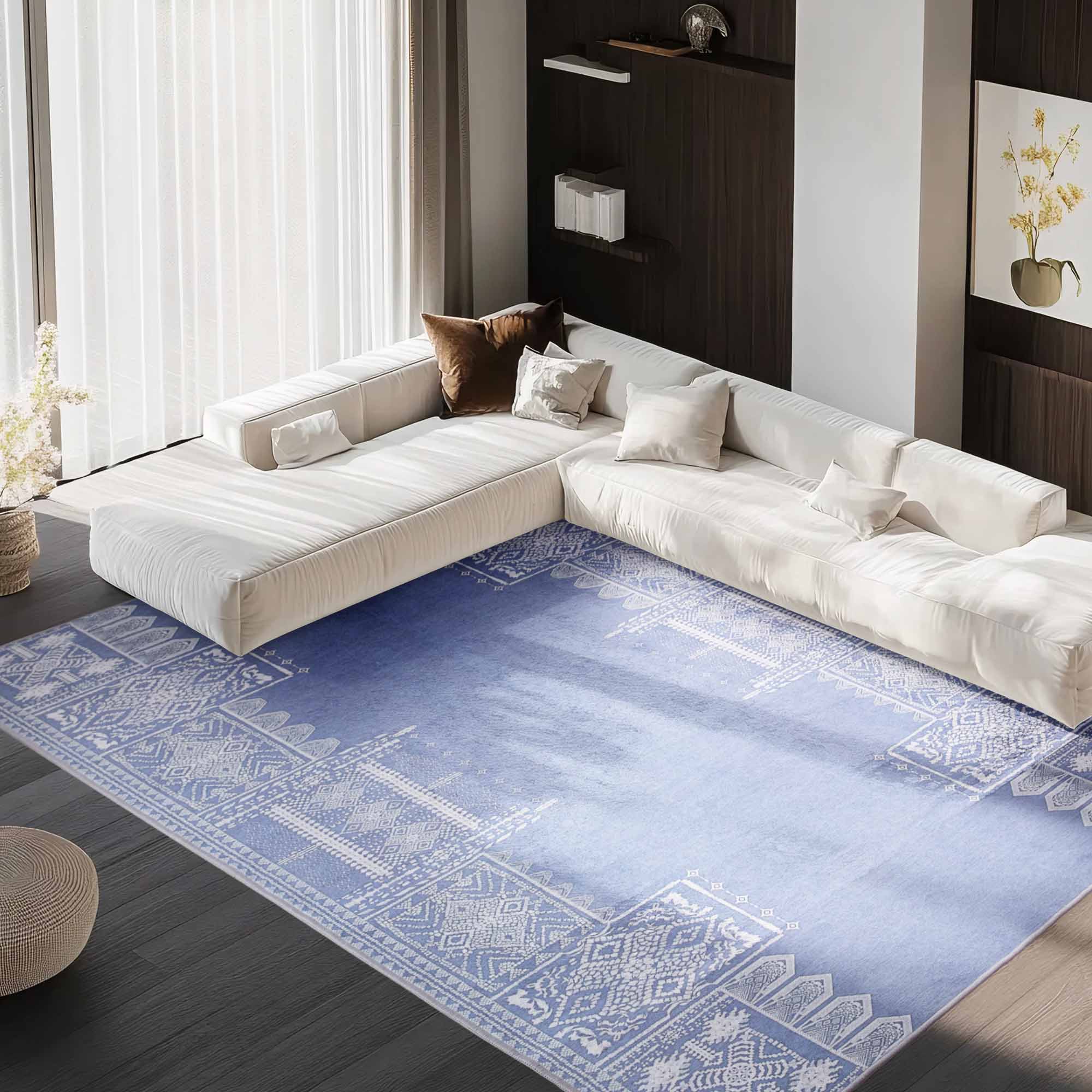 Light blue Faux Wool Mobius rug with white geometric patterns under a white sectional sofa in a modern living room.