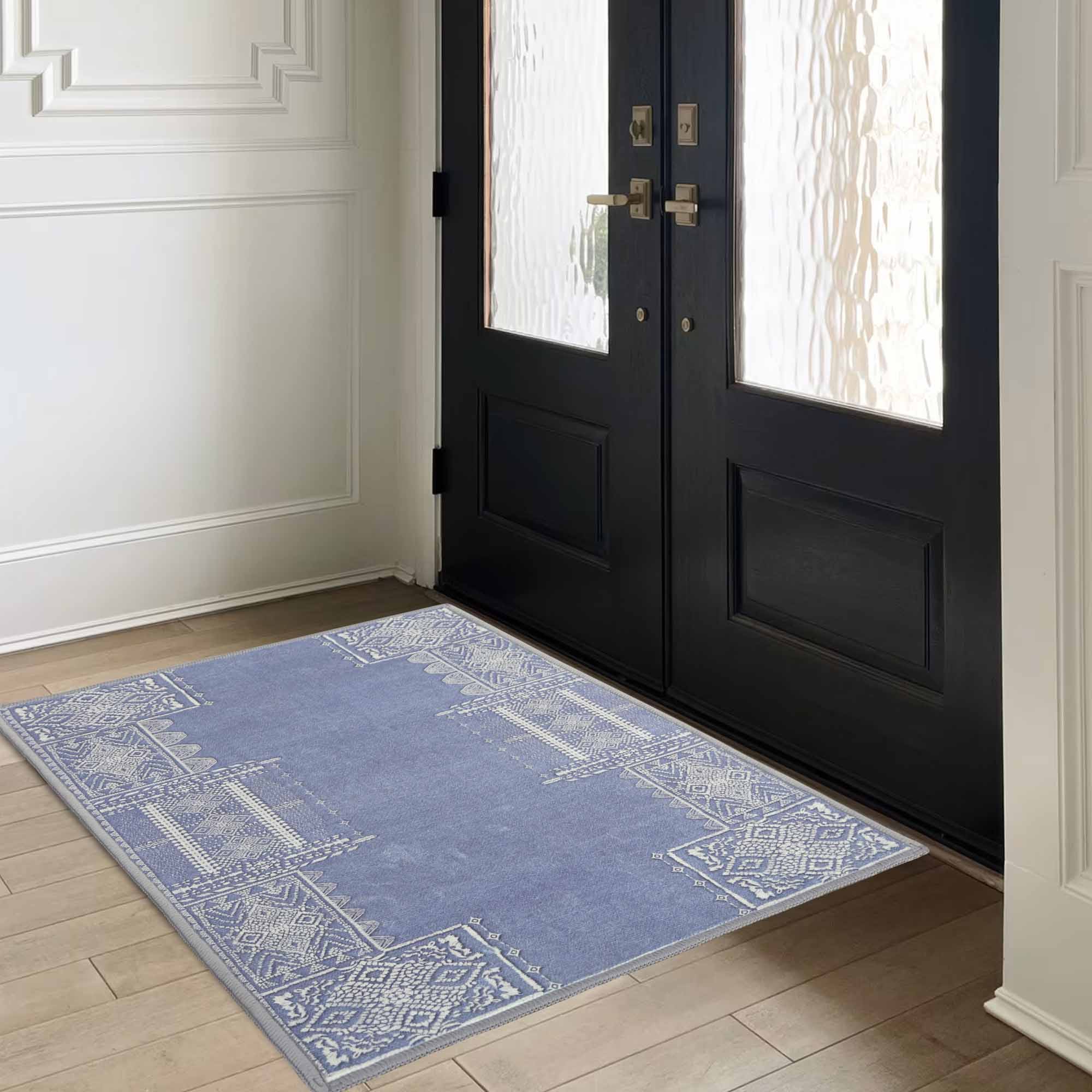 The Dream of Mobius periwinkle faux wool rug with white geometric patterns on light wood flooring in a home entryway.