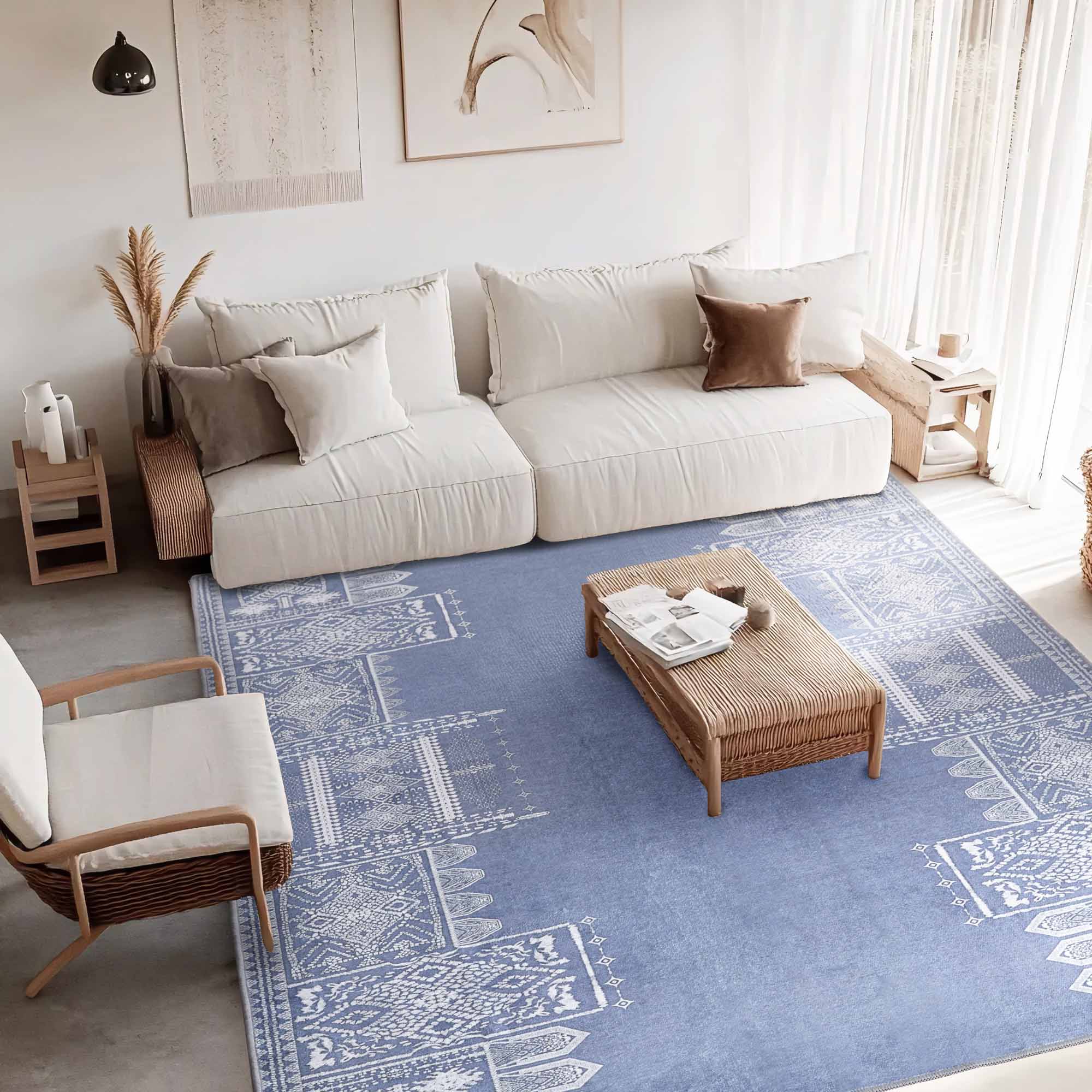 Overhead view of a living room featuring a large blue Faux Wool Rug with white geometric 'Dream of Mobius' patterns under a white sofa and woven coffee table.
