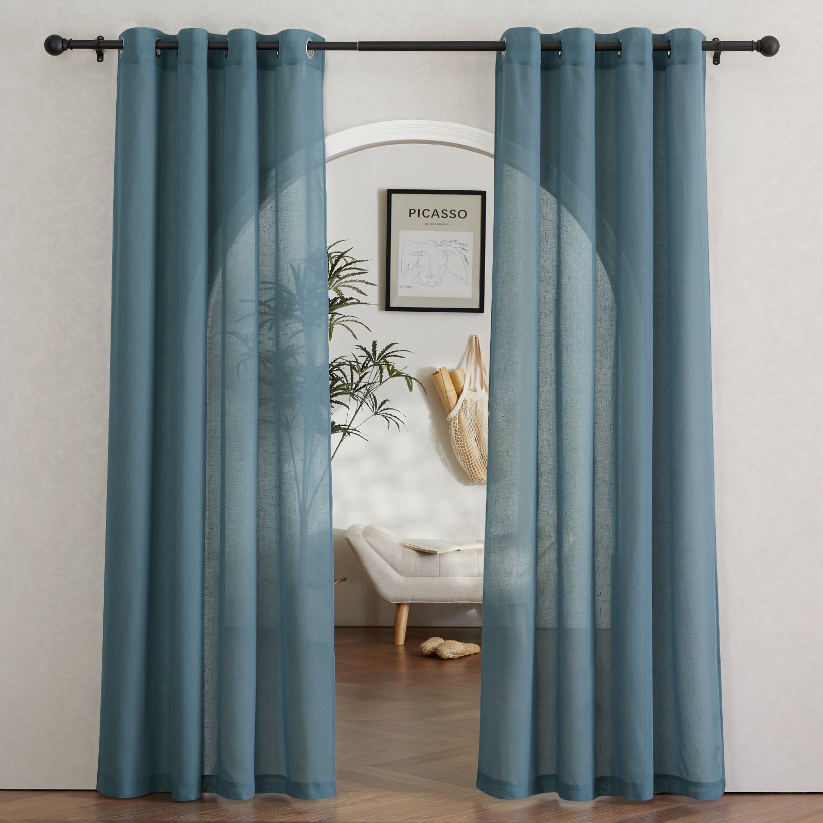 Two dusty blue faux linen sheer curtains with grommets hanging on a rod, parted to frame a view into another room.