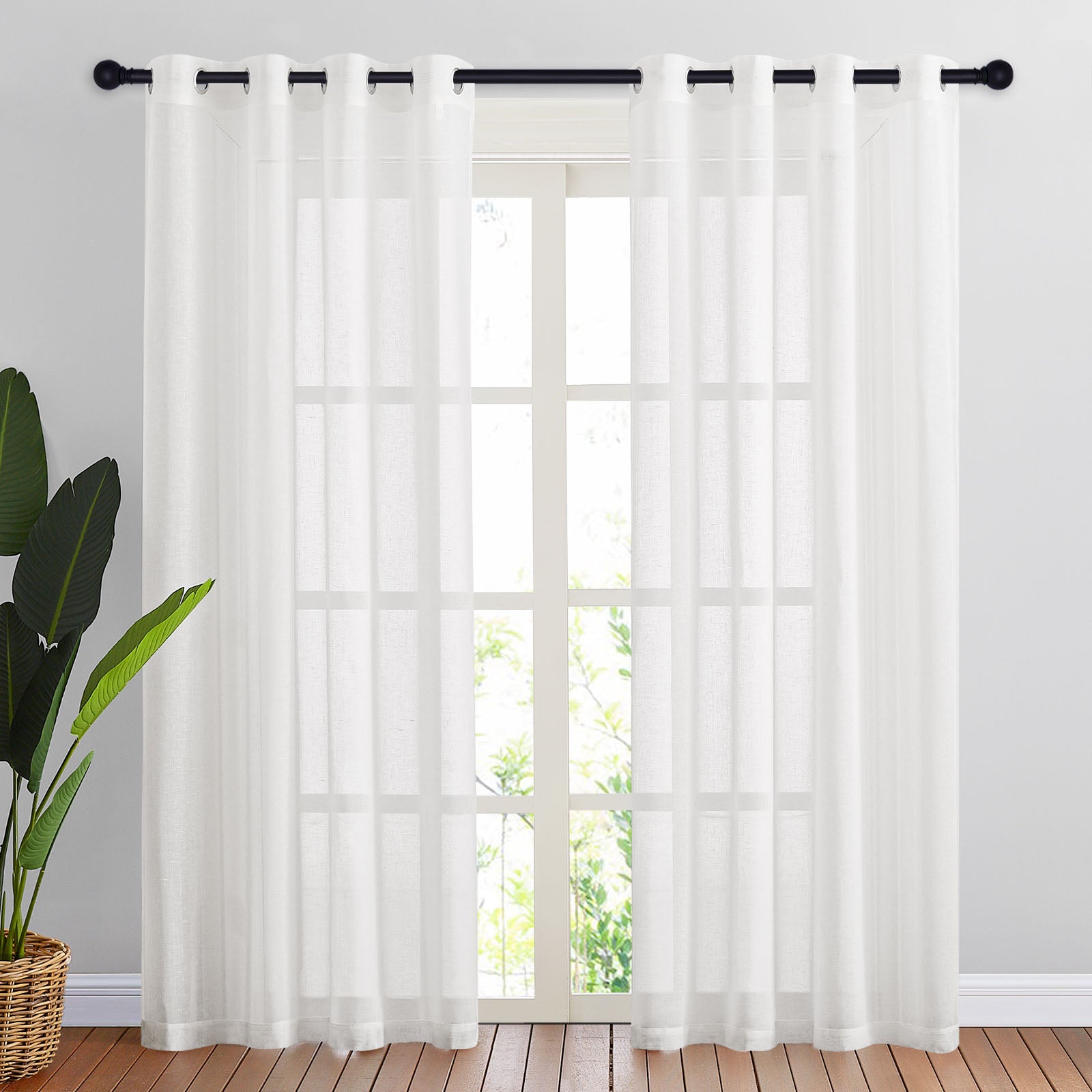 White faux linen sheer curtains on a black grommet rod, filtering sunlight into a bright room with a large window.
