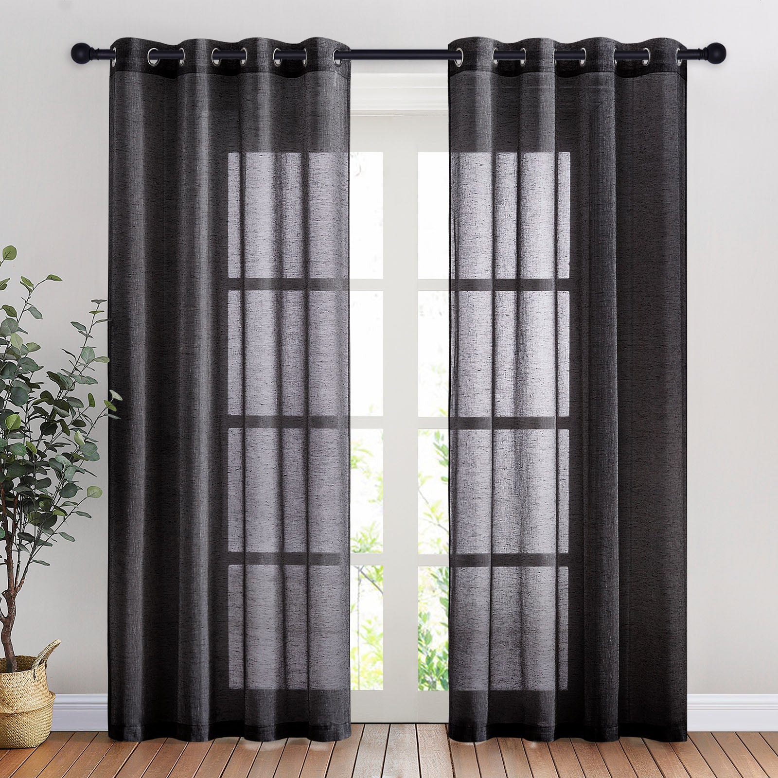 Black faux linen sheer curtains with metal grommets hang on a rod, filtering light from a tall paned window.