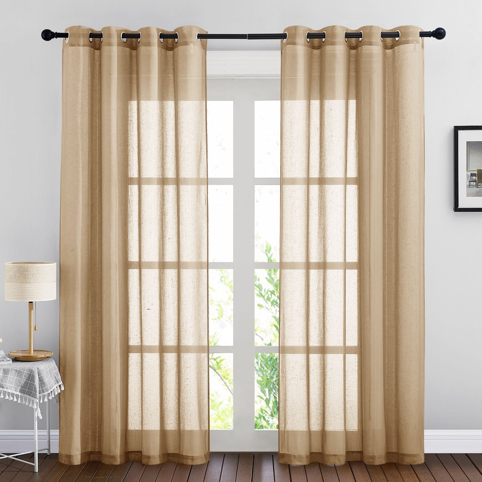 Two tan faux linen sheer curtain panels with grommets hung on a rod, filtering bright sunlight through a window.