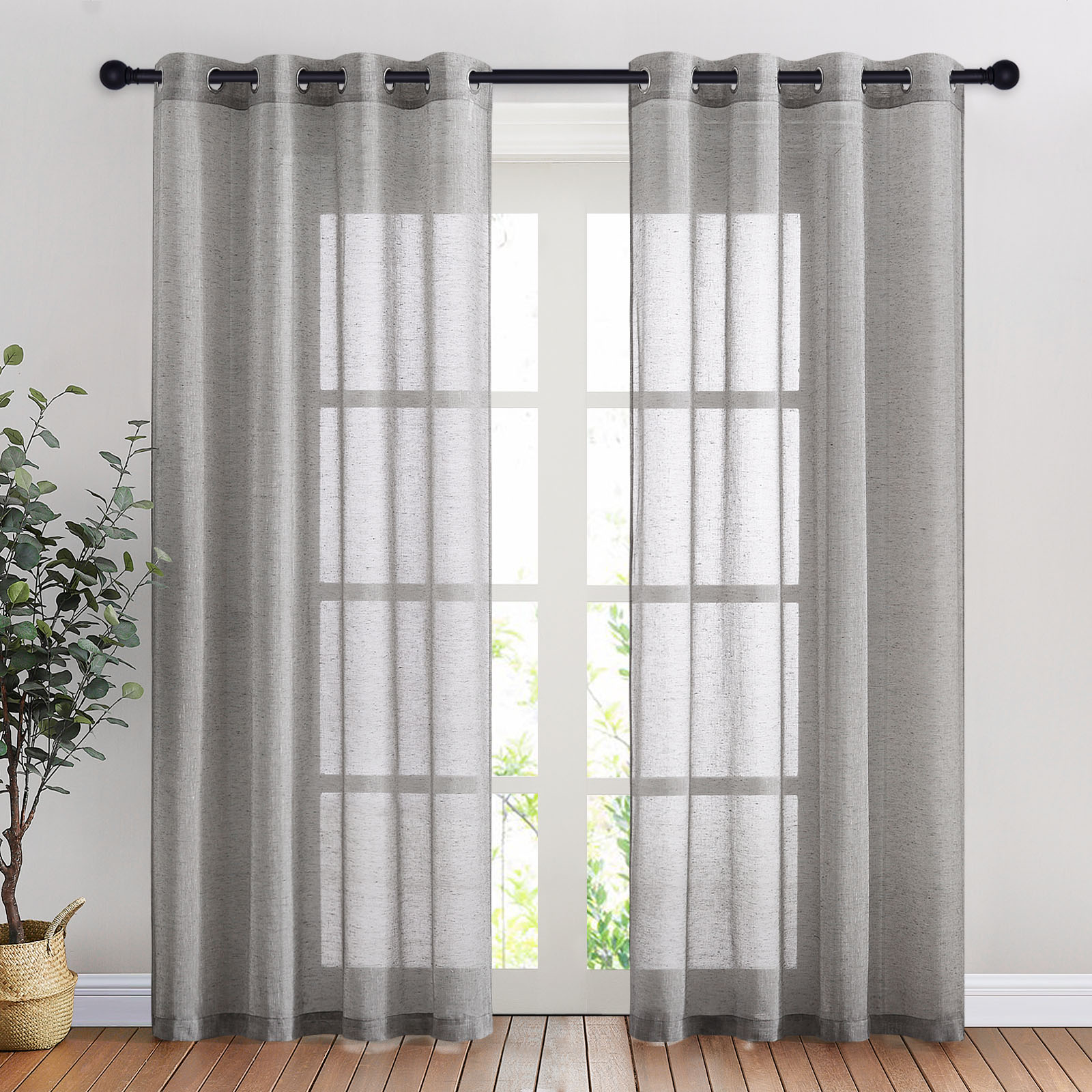 A pair of grey faux linen sheer curtains with silver grommets hang on a black rod, filtering light from a glass door.