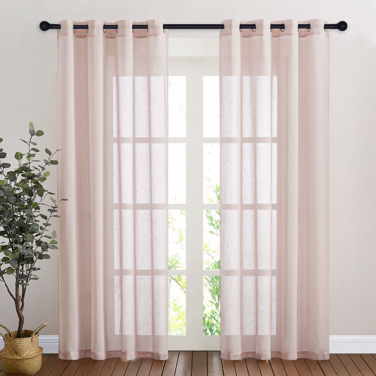 Pale pink faux linen sheer curtains with grommet tops hang over a bright window, filtering sunlight into a room.