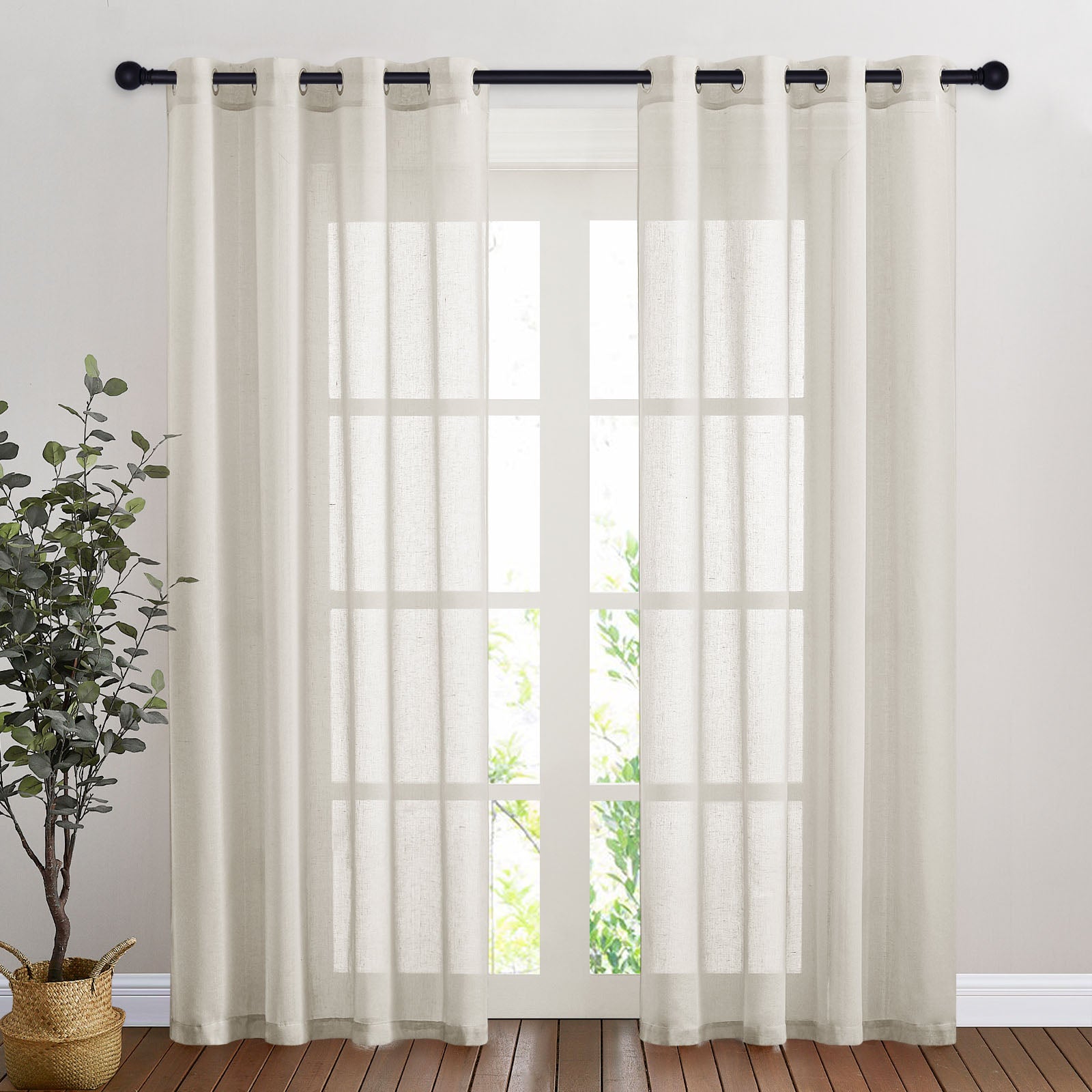 A pair of off-white faux linen sheer curtains with grommet tops hanging on a dark rod over a multi-pane glass door.