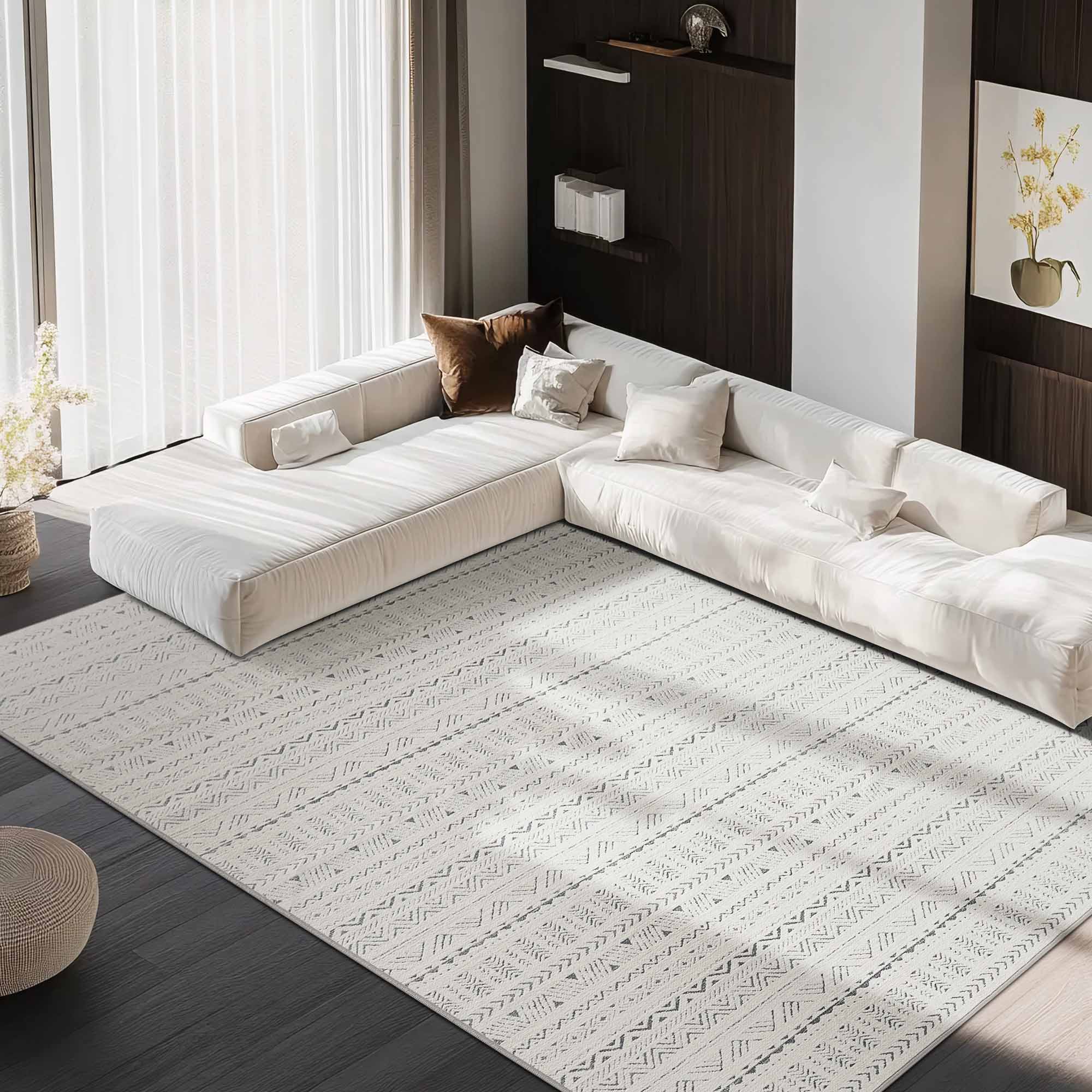 Light gray Tubekale Moroccan Jacquard chenille area rug with geometric pattern under a modern white sectional sofa on dark wood flooring.