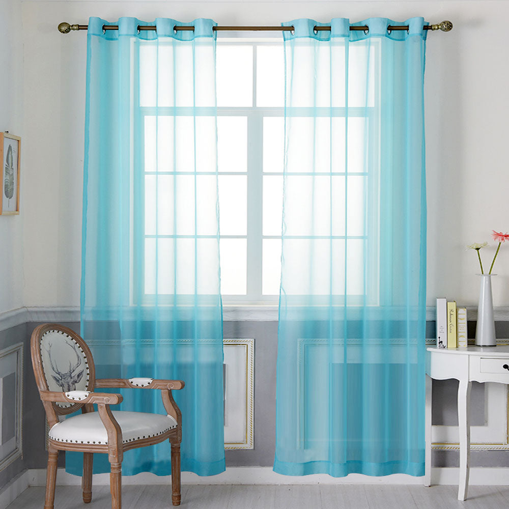 Light blue sheer grommet curtains hanging over a large window, filtering natural light into a neutral-toned room.