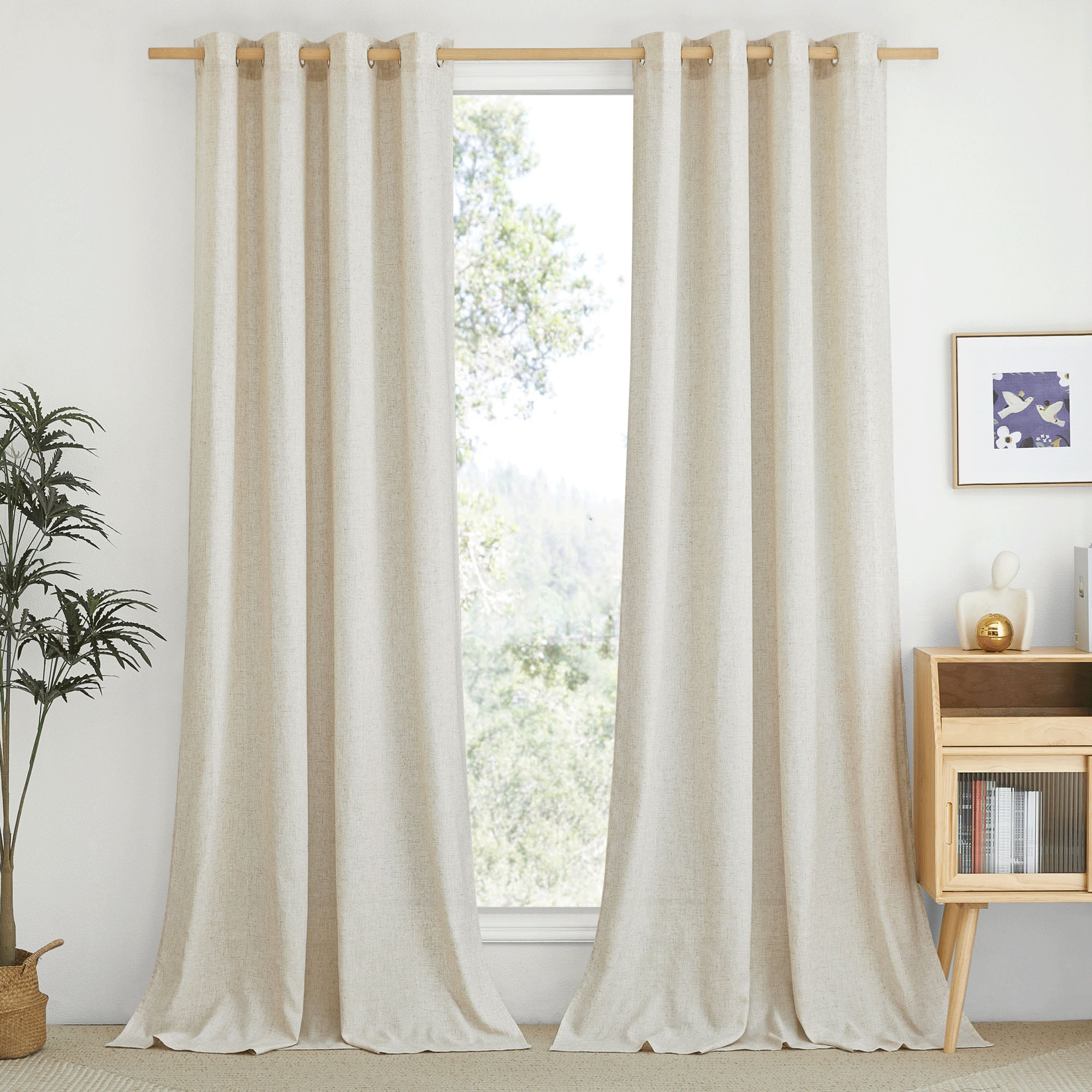 A pair of natural semi-sheer linen curtains with grommets hanging on a wood rod, softly filtering light into a living room.