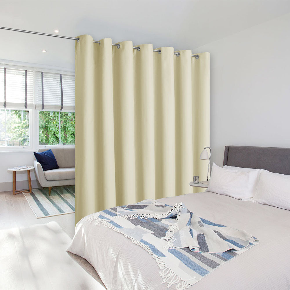 Cream grommet top room divider curtain on a tension rod creating a private bedroom space next to a living area.