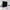 A black room divider curtain with silver grommets separating a bedroom from a living area in a bright, modern apartment.