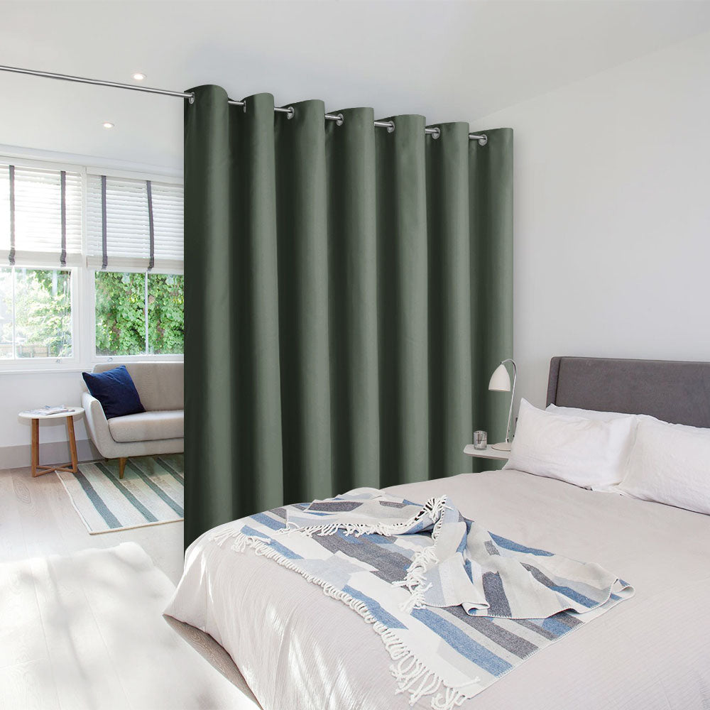 Dark green room divider curtain on a tension rod separating a bedroom from a bright, modern living room space.