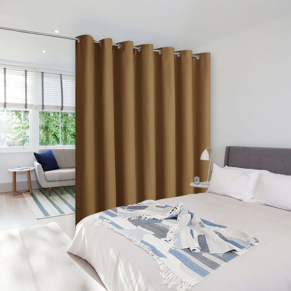 A brown grommet-top room divider curtain hung on a rod to create a private sleeping space next to a sitting area.