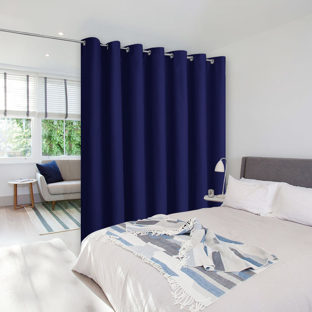 A navy blue room divider curtain creates a private bedroom space, separating it from an adjacent sunlit living area.