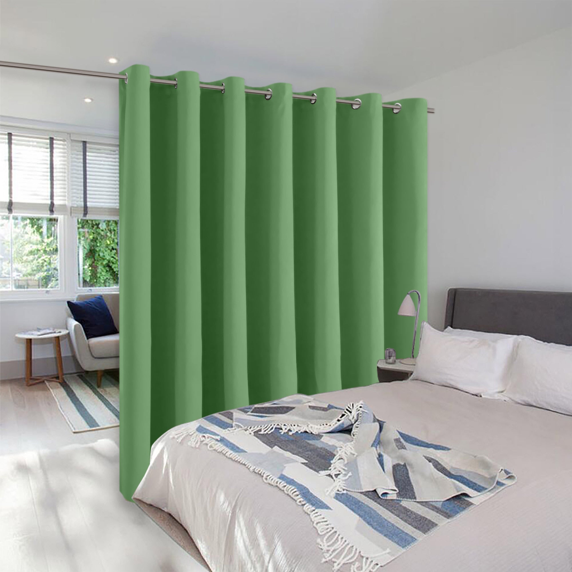 A green grommet room divider curtain creates a private partition between a bedroom and a small, well-lit sitting area.