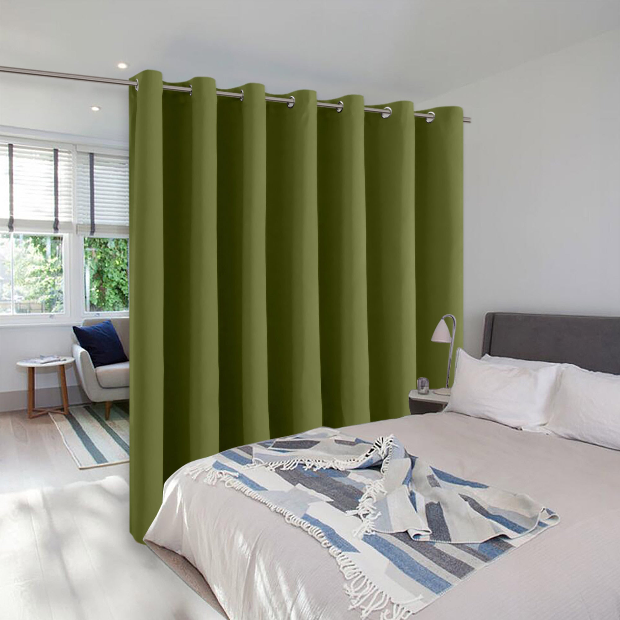 Olive green room divider curtain with silver grommets creating a private sleeping area in a modern, open-plan room.