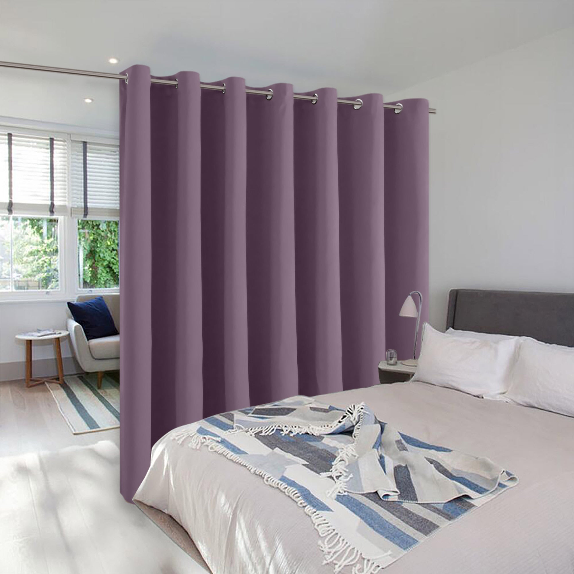 Mauve purple room divider curtain with grommets hung on a rod to separate a bedroom from a bright sitting area.