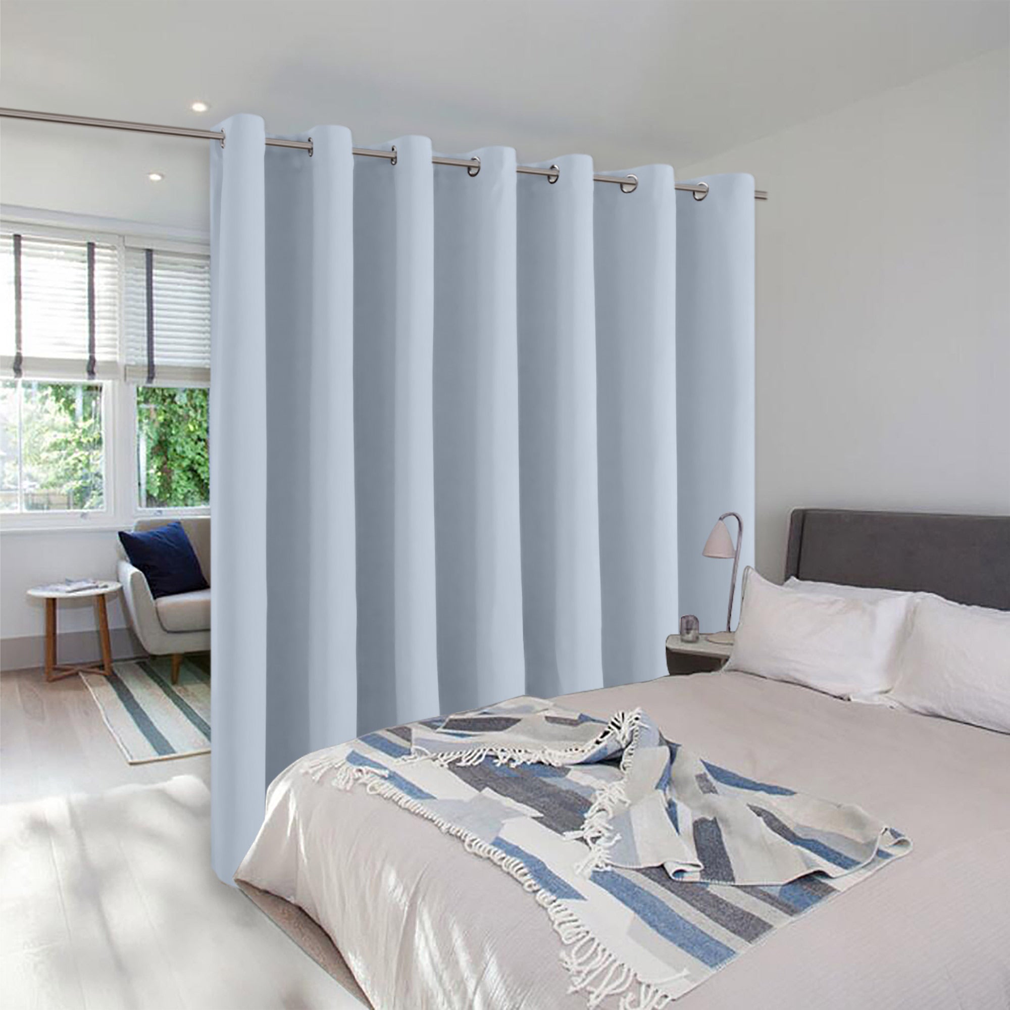 Light blue room divider curtain with grommets partitioning a modern bedroom to create a separate, private sleeping area.