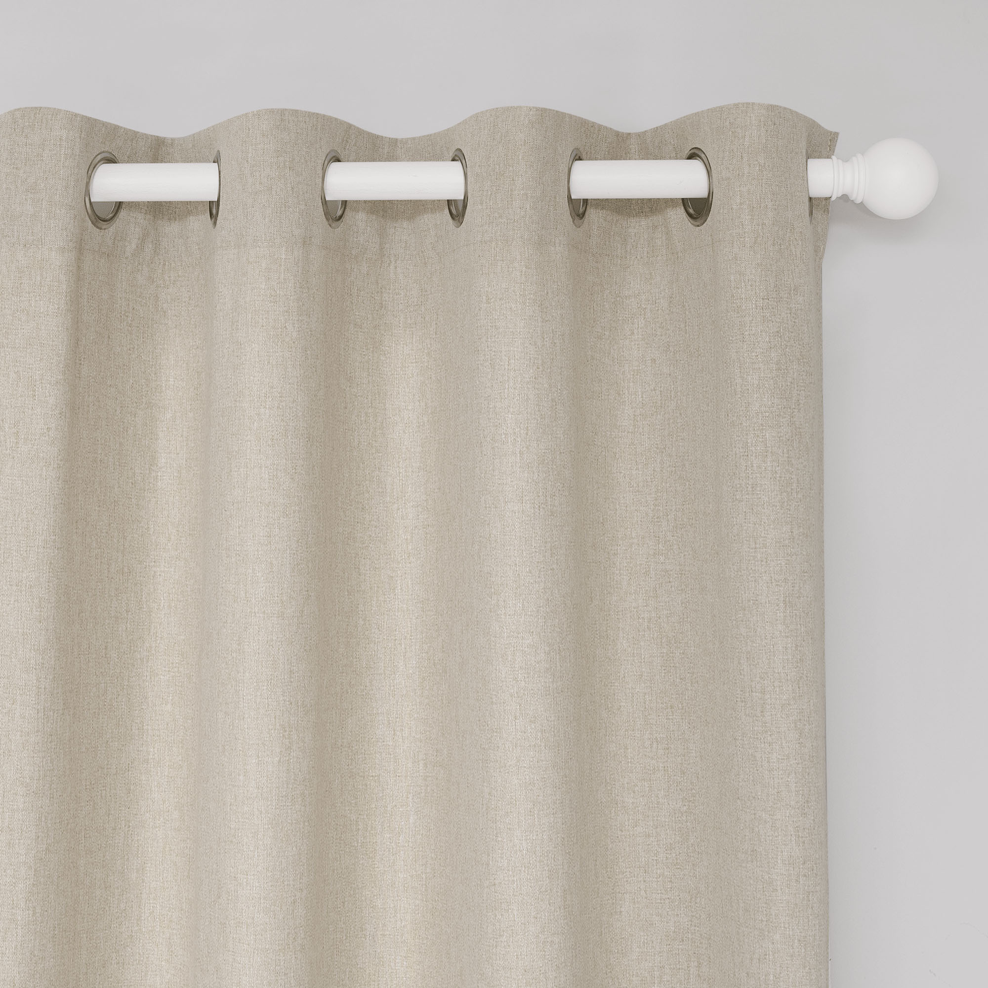 Close-up of a soft beige cotton linen curtain, showing detailed fabric texture, silver grommets, and white rod.