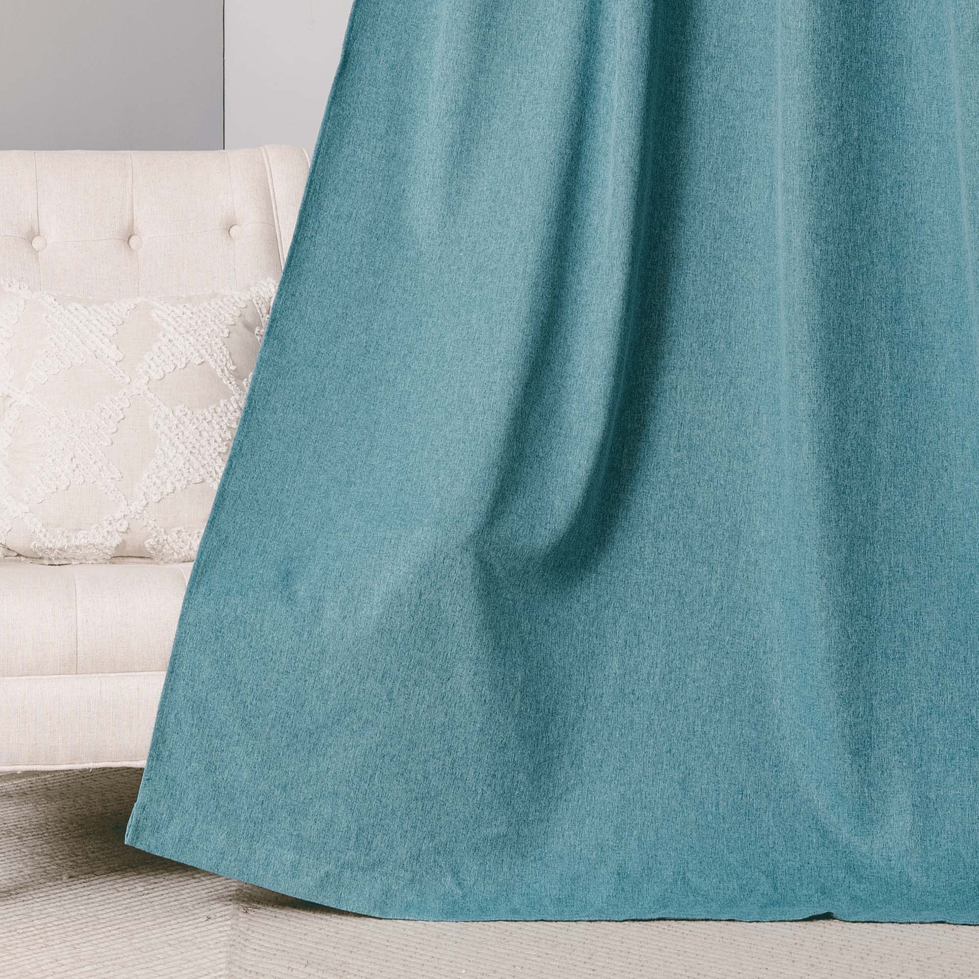 Close-up of a soft teal blue cotton linen curtain, highlighting its subtle texture and natural drape, beside a beige tufted chair.